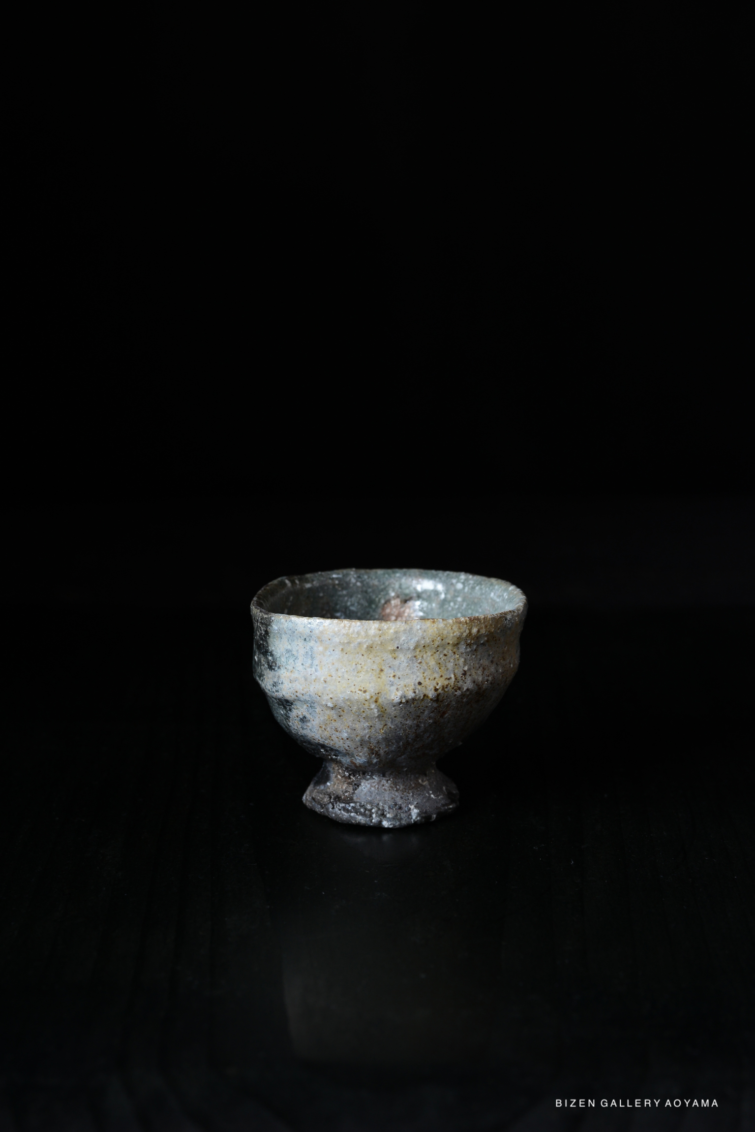 A ceramic bowl with a textured surface and a round base, displayed against a dark background.