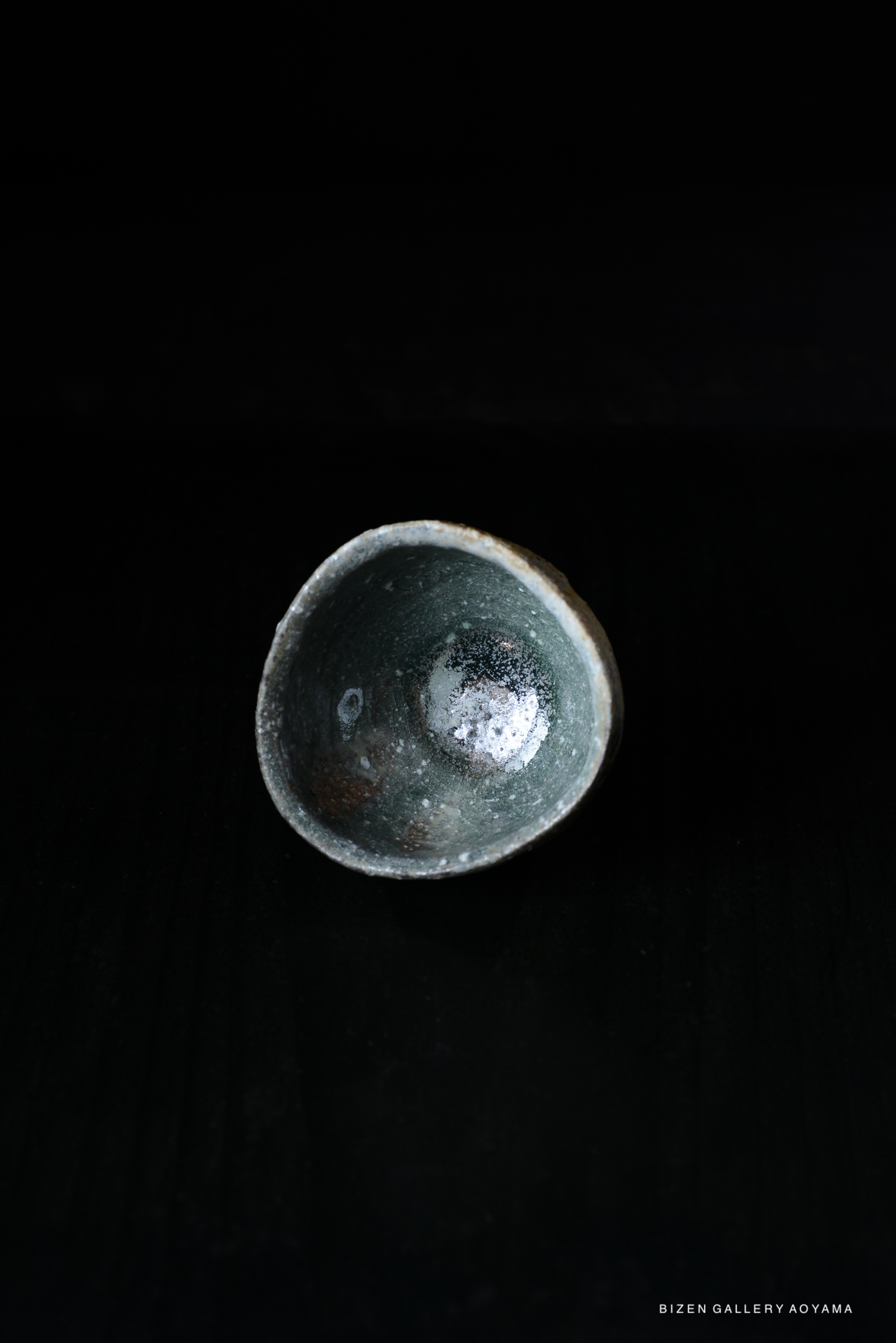 Iga ceramic guinomi featuring a unique glaze, shown against a dark background.