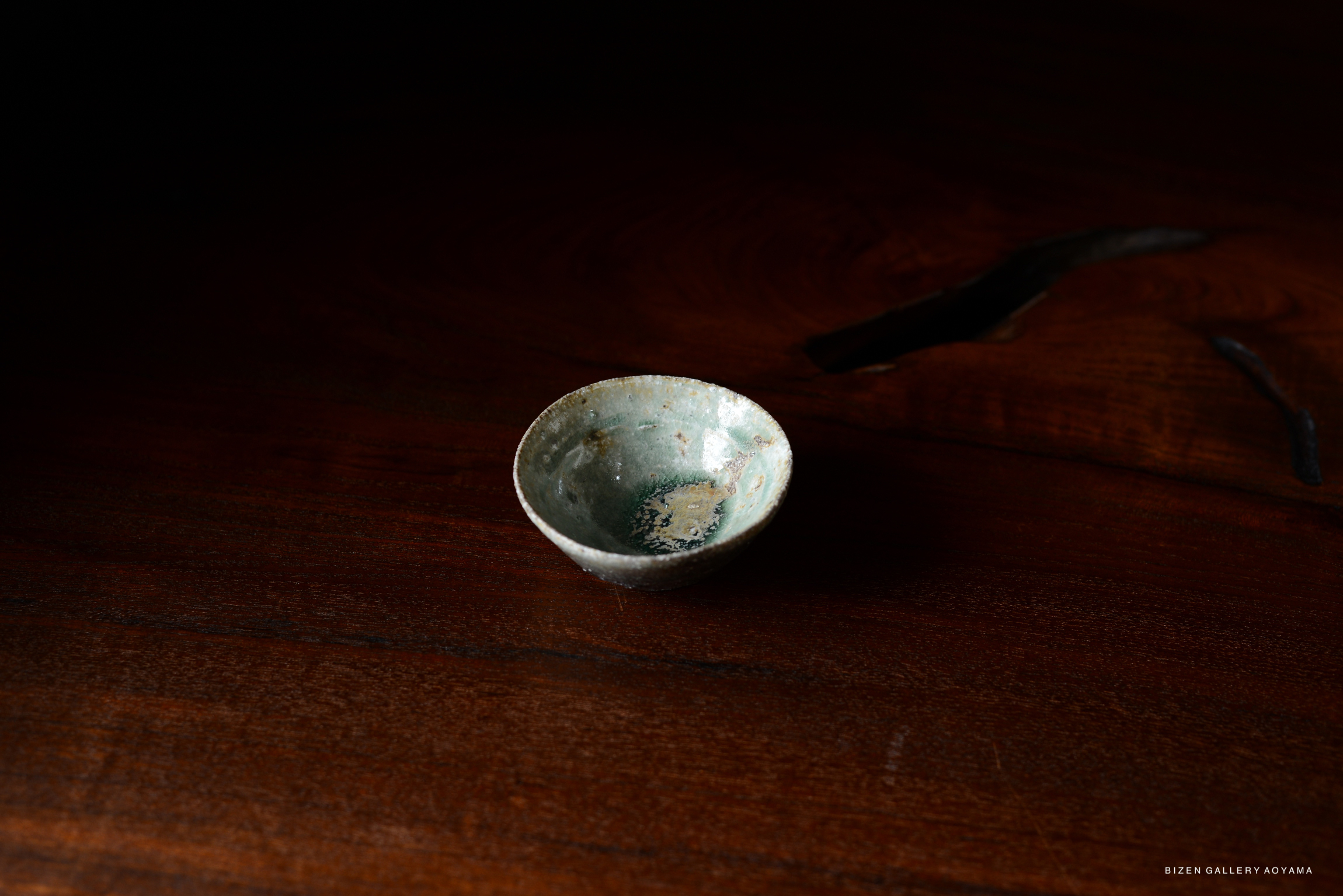 A small Iga ceramic bowl with a textured surface, placed on a dark wooden table.
