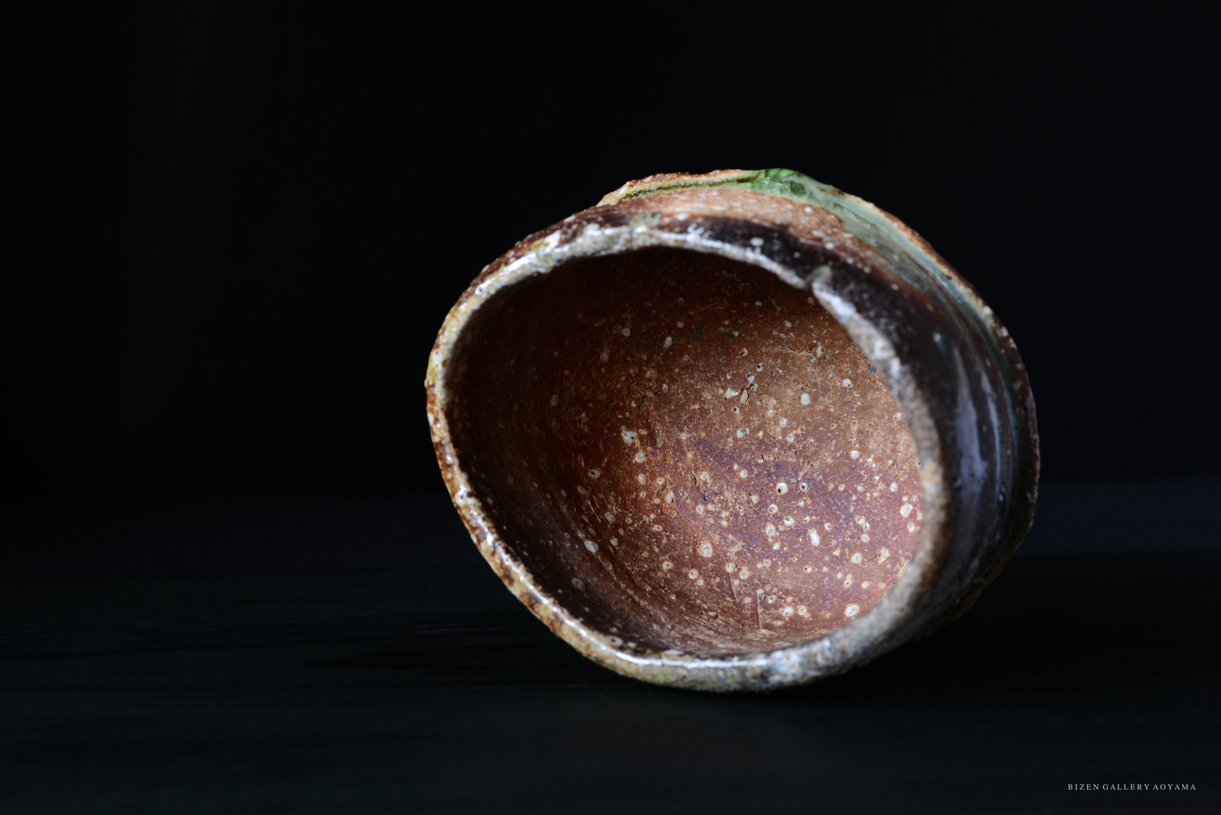 暗い背景に置かれた、素朴な質感の焼き物の内側の写真