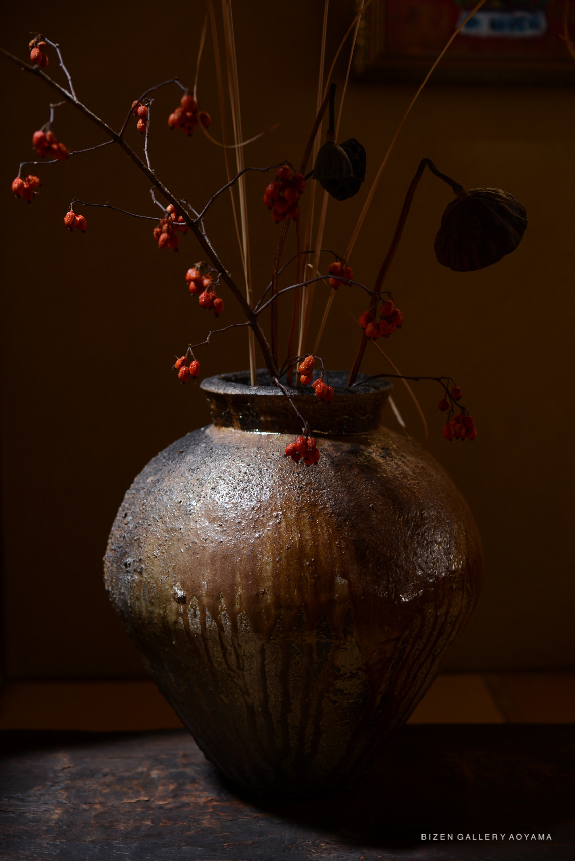 A beautifully crafted Bizen Otsubo pottery vase adorned with dried orange berries and delicate twigs, displayed in soft lighting.