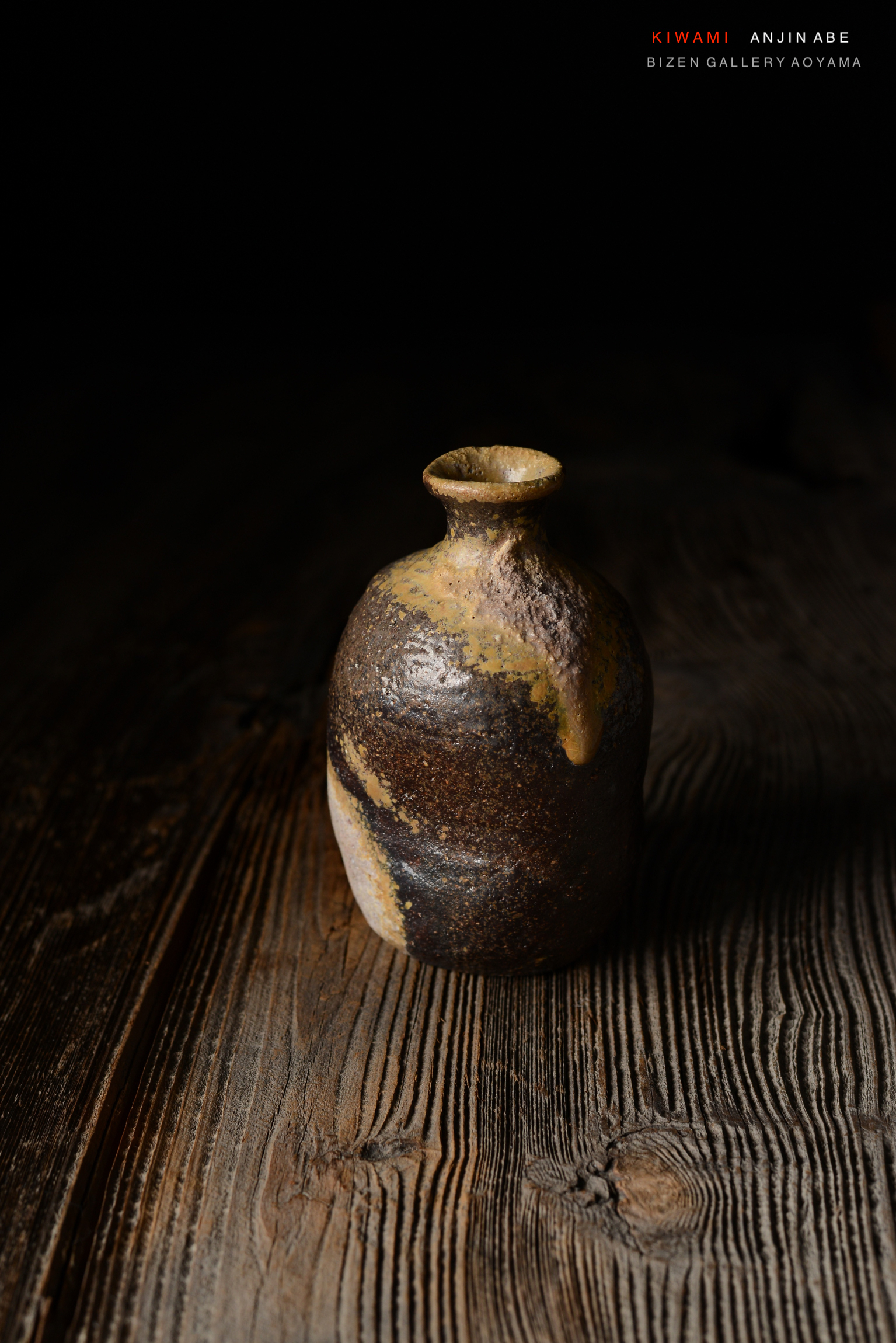 暗い背景に置かれた、独特の形状を持つ焼き物の壺が木のテーブルの上に置かれている