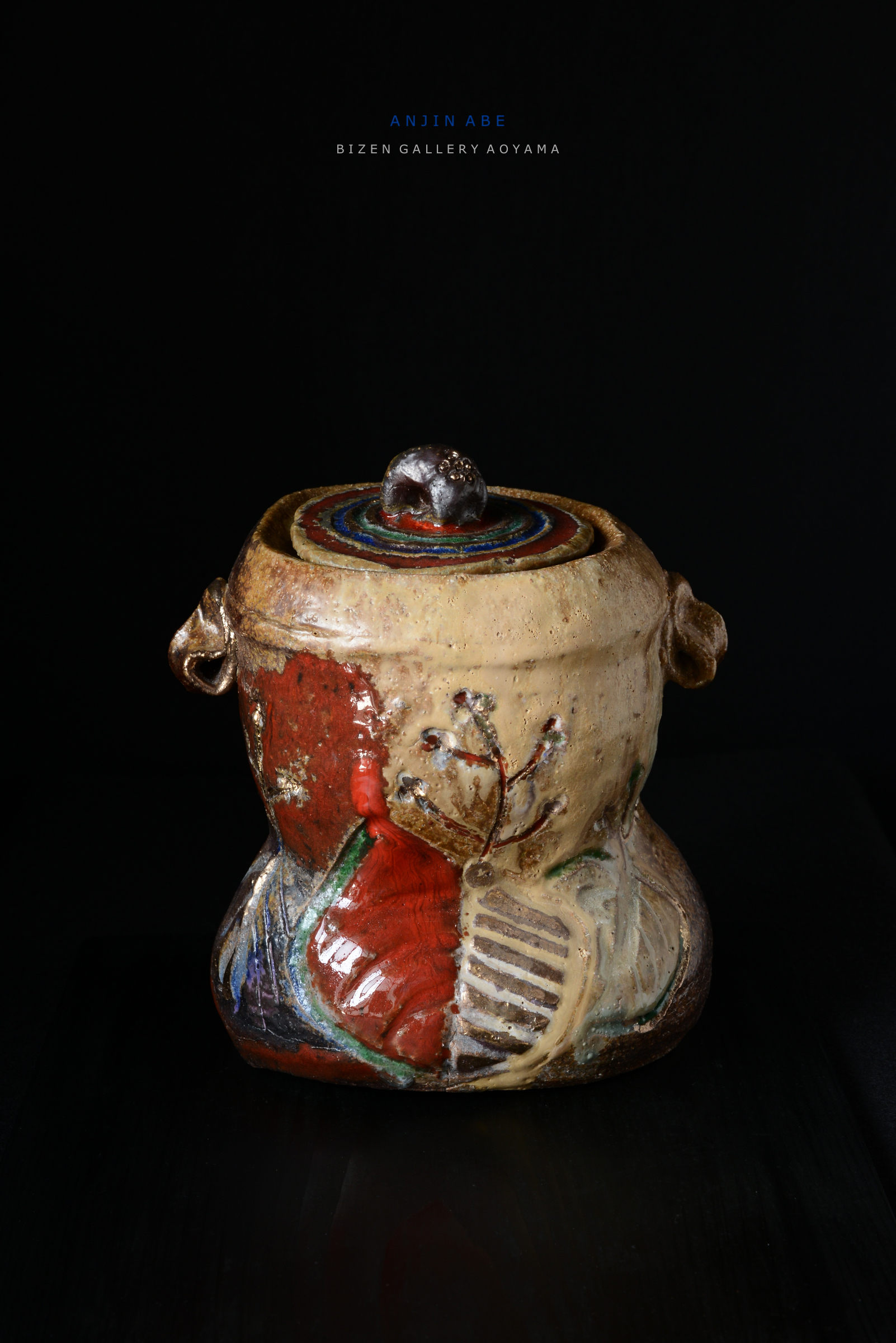 色とりどりの模様が施された陶器の壺、上部に金属製の飾りがあり、暗い背景で際立っています。