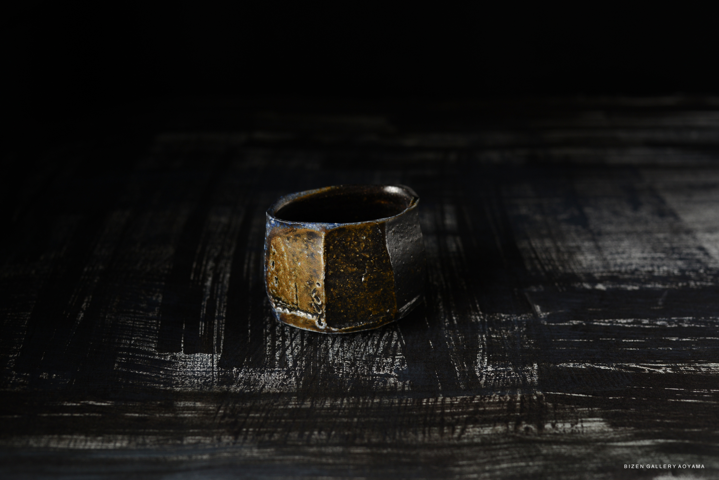 A Bizen pottery small bowl with a rustic, textured surface, set against a dark background.