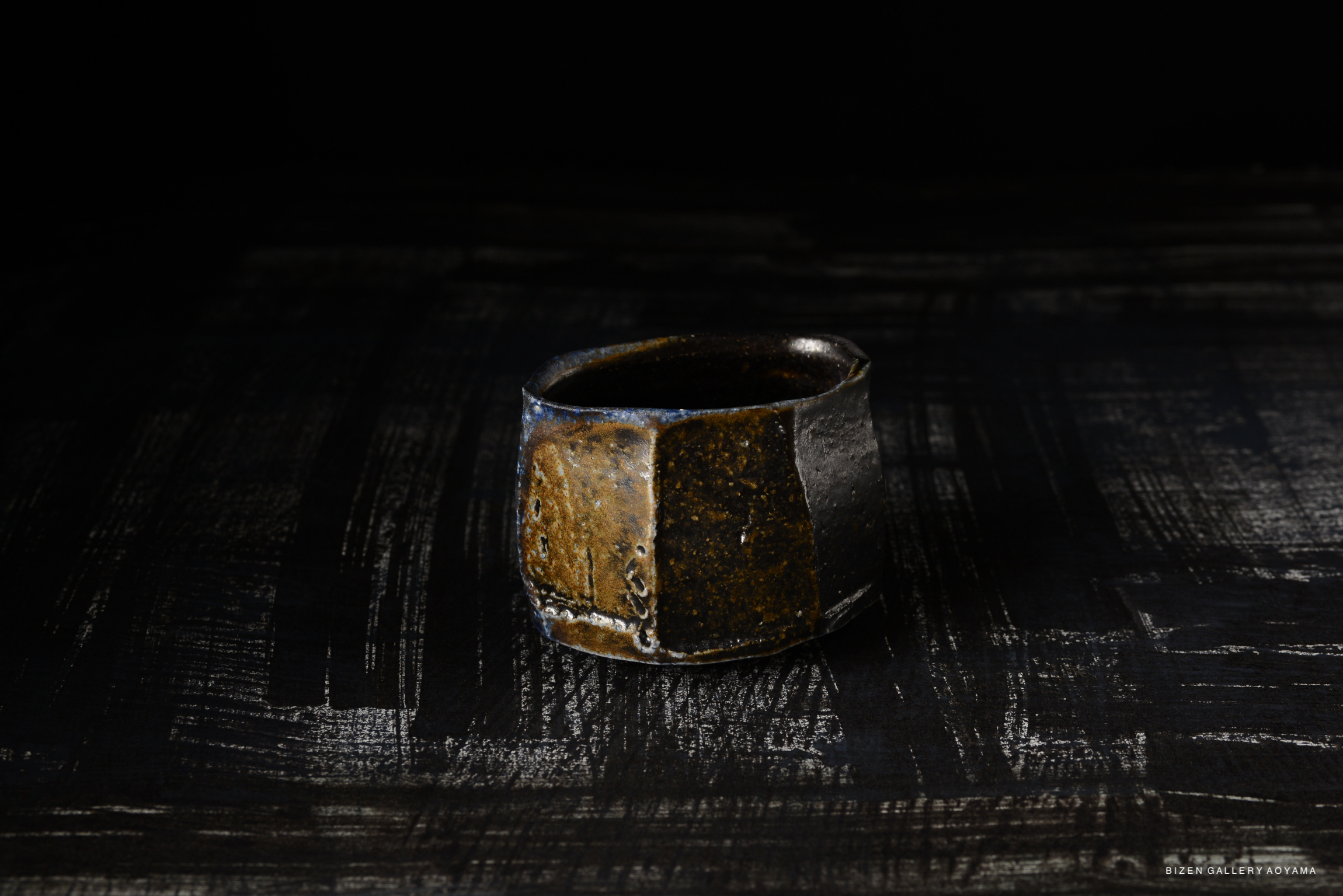 Bizen Kofukuwan, a traditional Japanese small serving bowl, showcasing a unique glaze with earthy tones, elegantly placed on a textured dark surface.