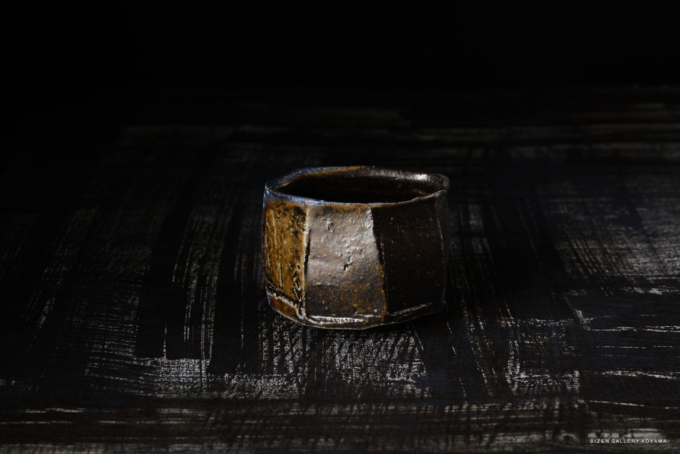 Bizen Kofukuwan, a small ceramic bowl with unique texture and color, resting on a dark surface.