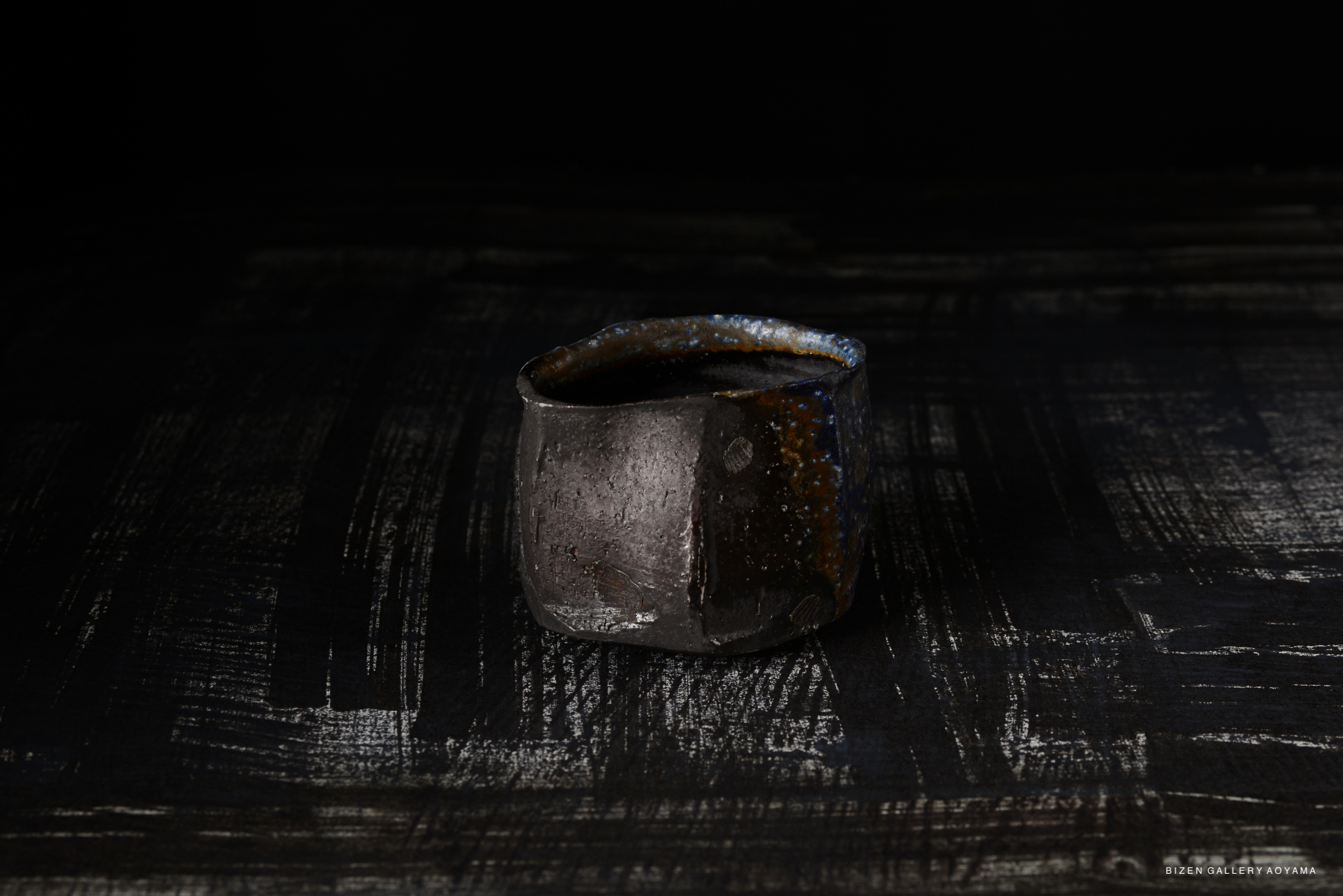 A Bizen-style small bowl on a textured dark background, showcasing earthy tones and a handmade appearance.