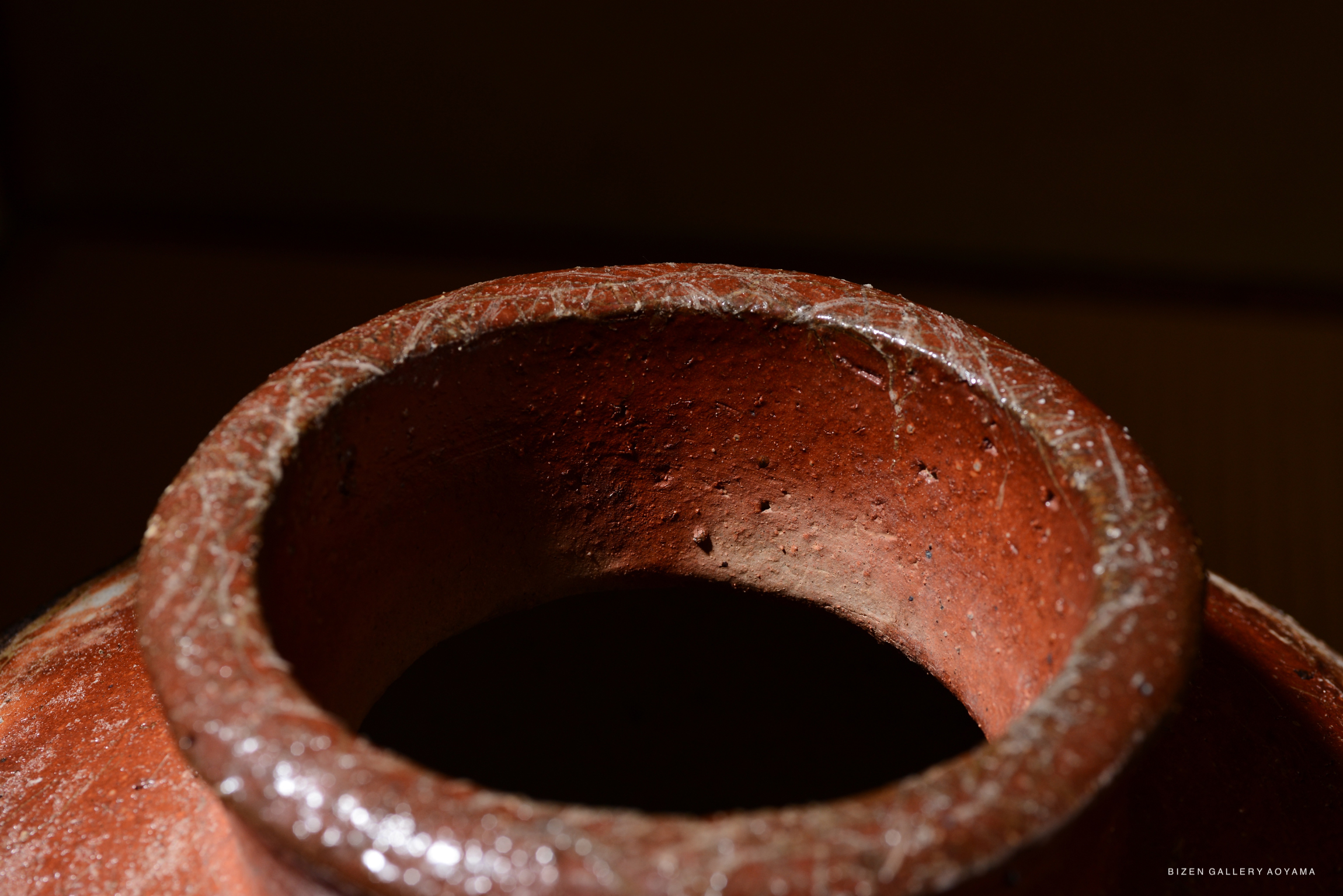 Close-up view of the rim of a Bizen tsubo pottery piece, featuring a textured surface and earthy tones.