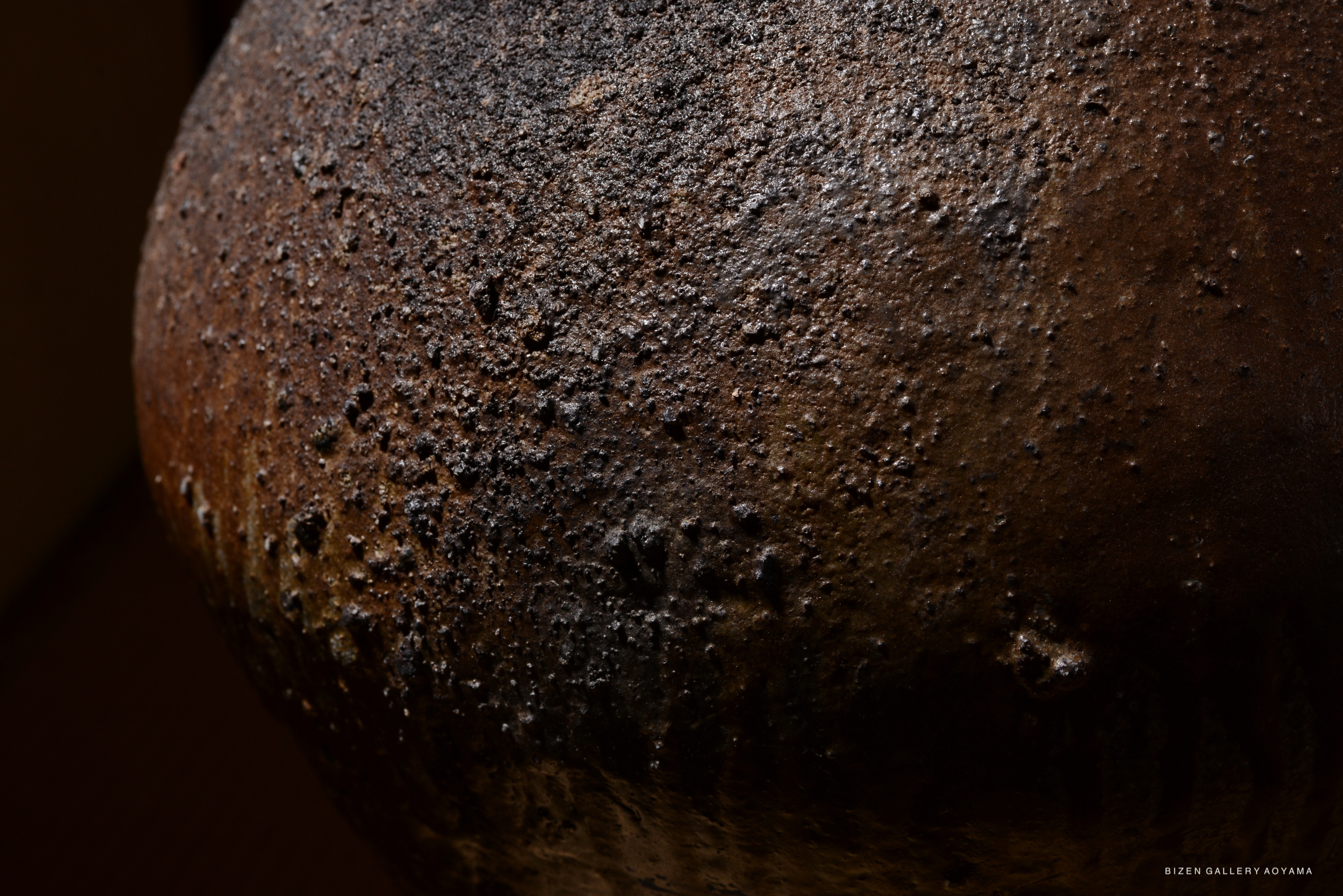 Close-up view of a rustic Bizen pottery piece, showcasing its textured surface and earthy tones.