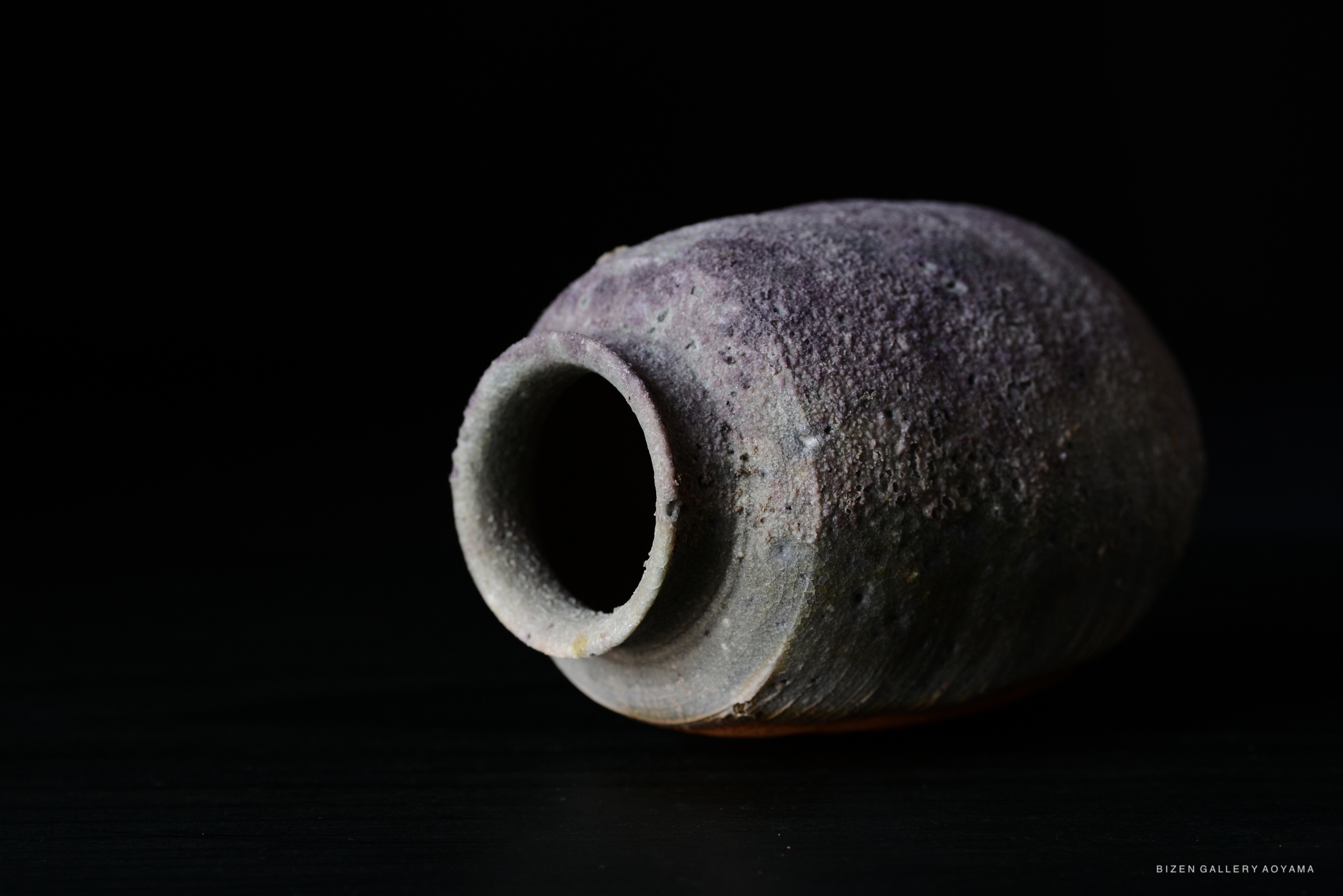 Close-up of a Kotsubo (Chaire), a traditional Japanese tea container, with a textured surface and rounded shape, set against a dark background.