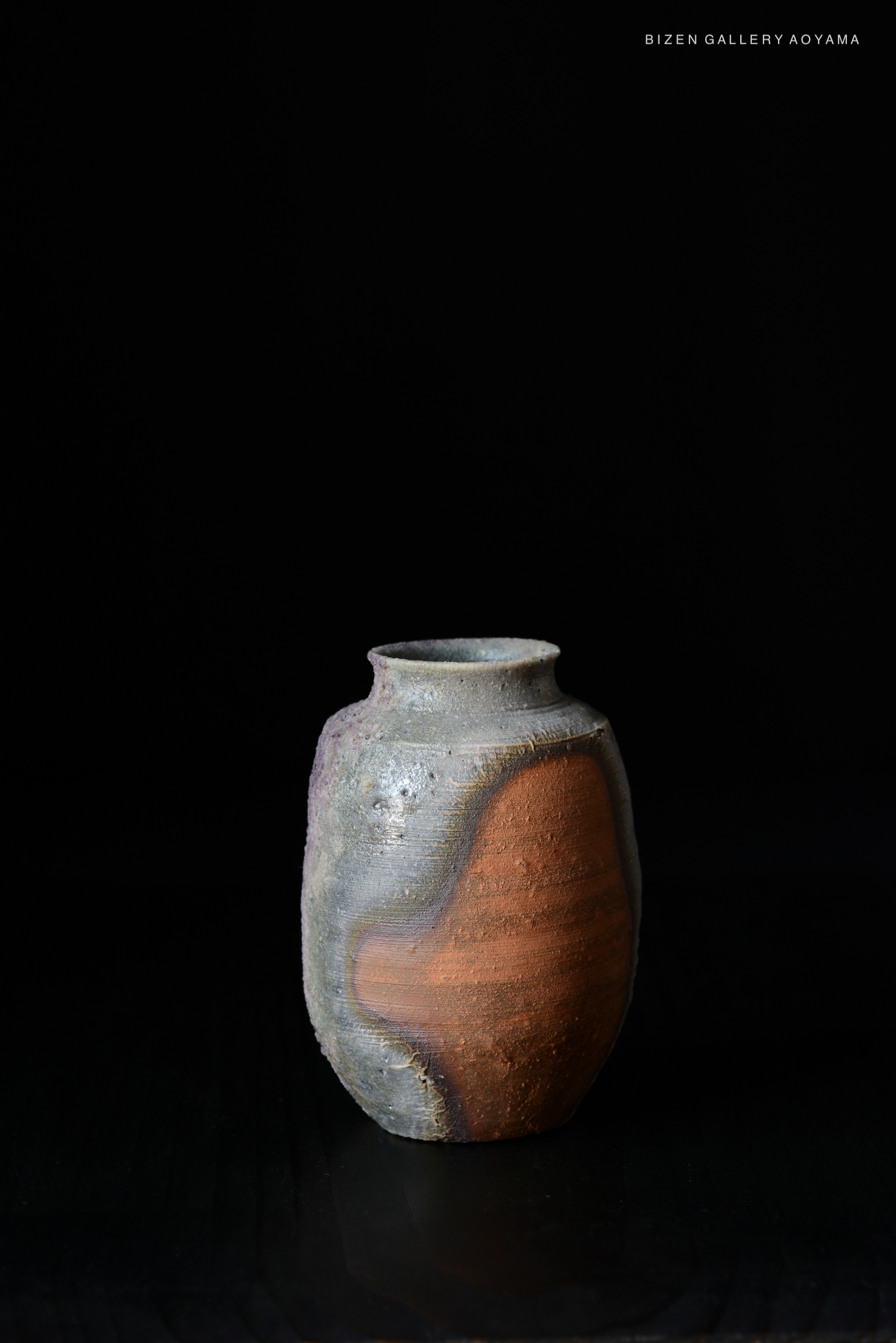 A traditional Bizen pottery vase with a unique shape and earthy colors, set against a black background.