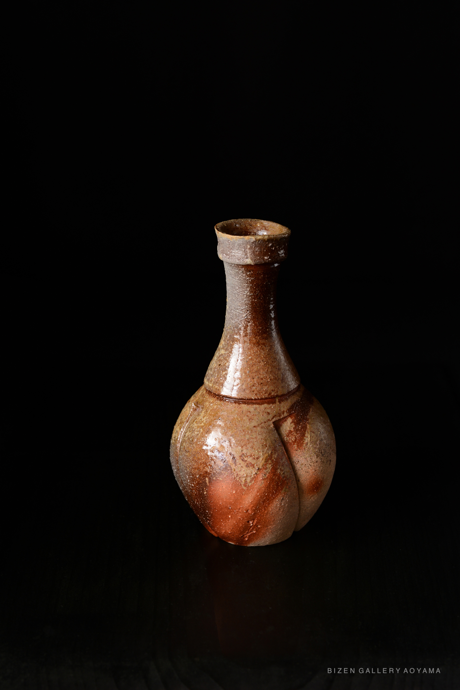 A traditional Bizen tokkuri with a rounded body and narrow neck, showcasing the natural earthy tones typical of Bizen pottery.