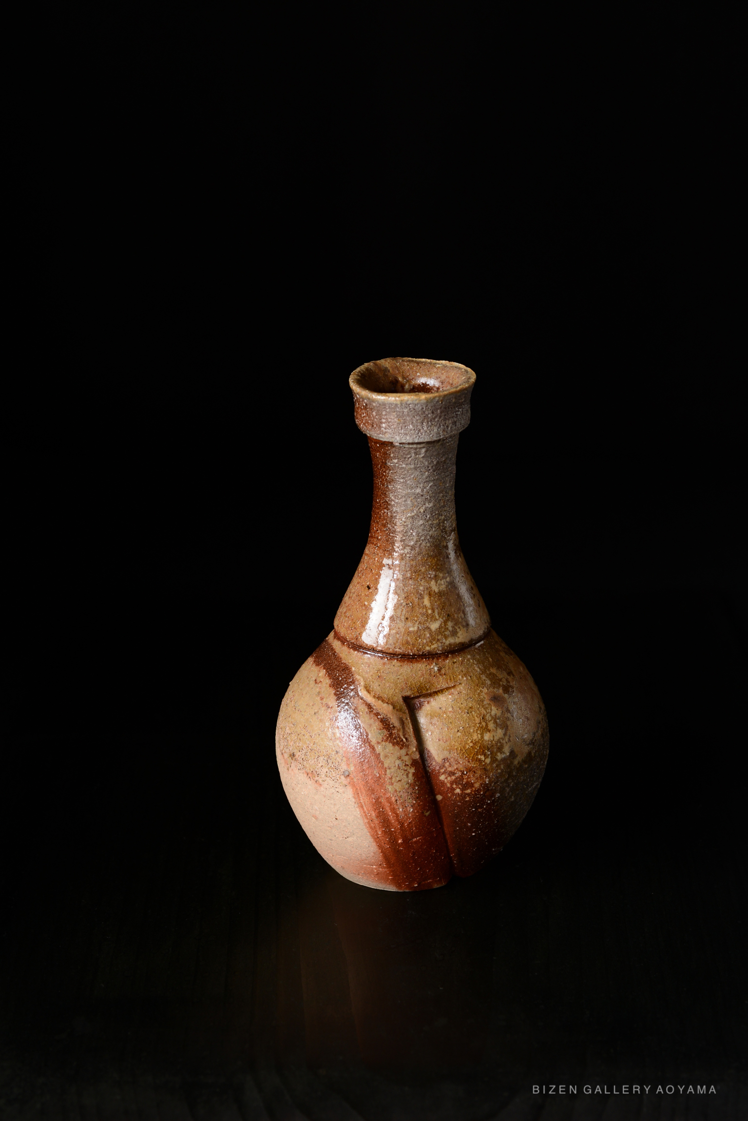 Bizen Tokkuri, a traditional Japanese ceramic sake bottle, featuring a unique glazed finish and a distinctively shaped body, set against a black background.
