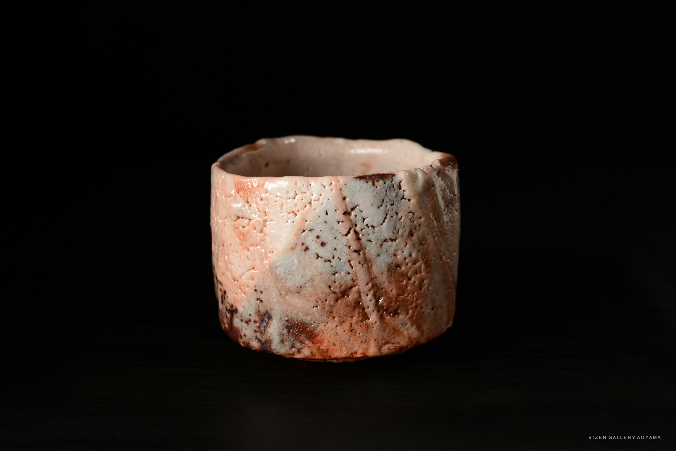 Shino Chawan, a ceramic teacup with a textured surface, exhibiting soft peach and white hues.