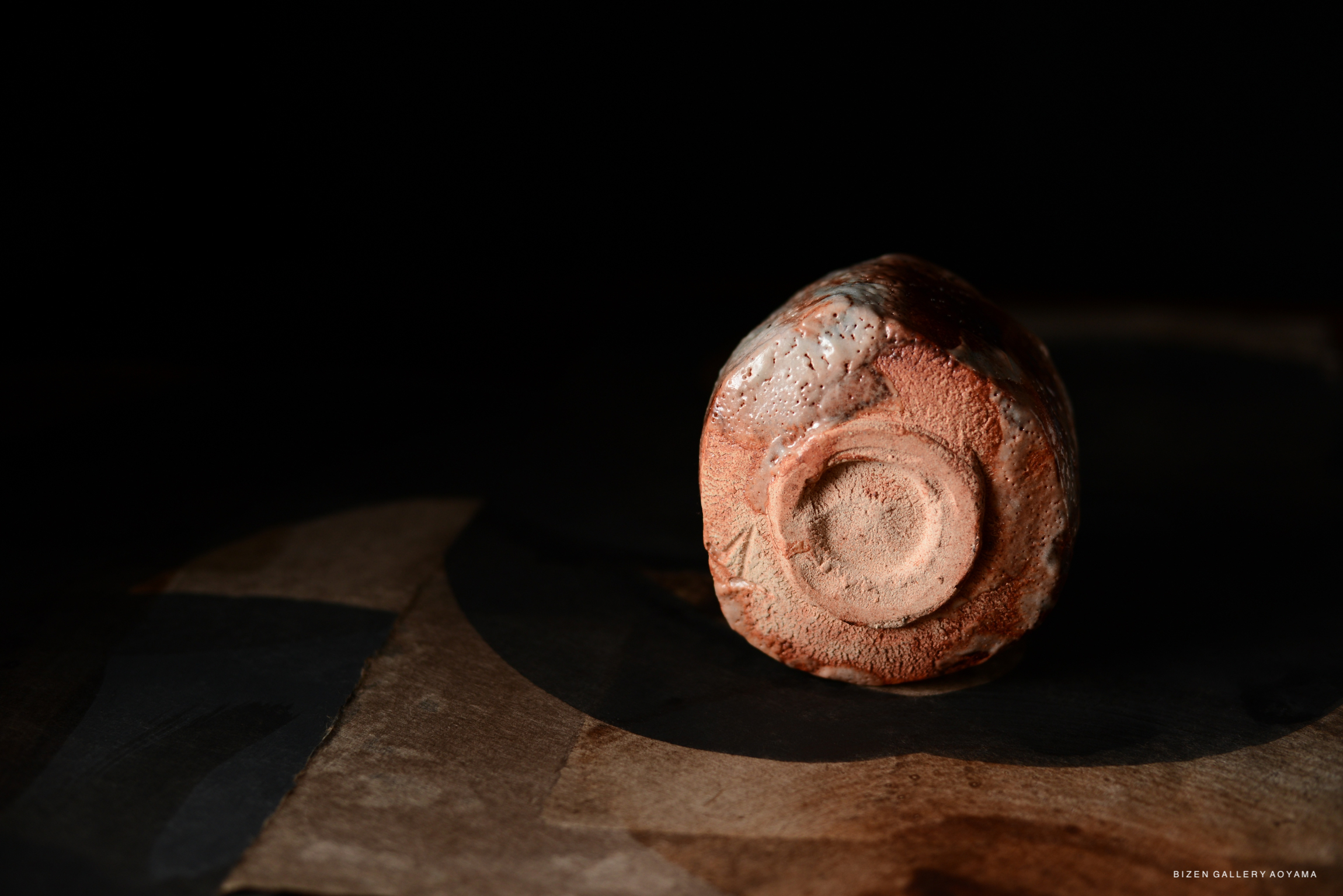 A close-up view of the bottom of a Shino Chawan tea bowl, showcasing its textured surface and earthy colors.