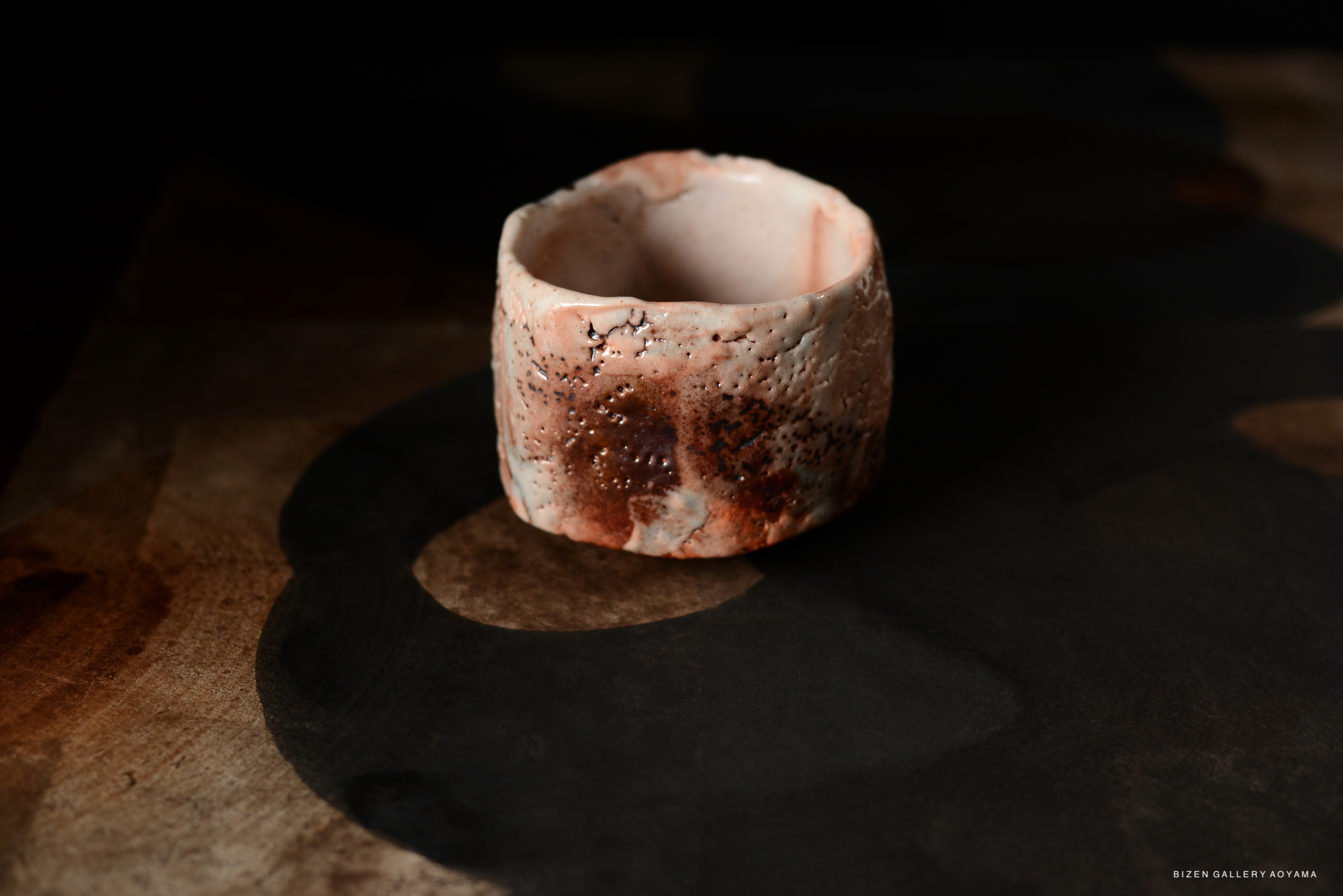 A hand-crafted Shino chawan (tea bowl) showcasing a unique texture and color with a wooden background.