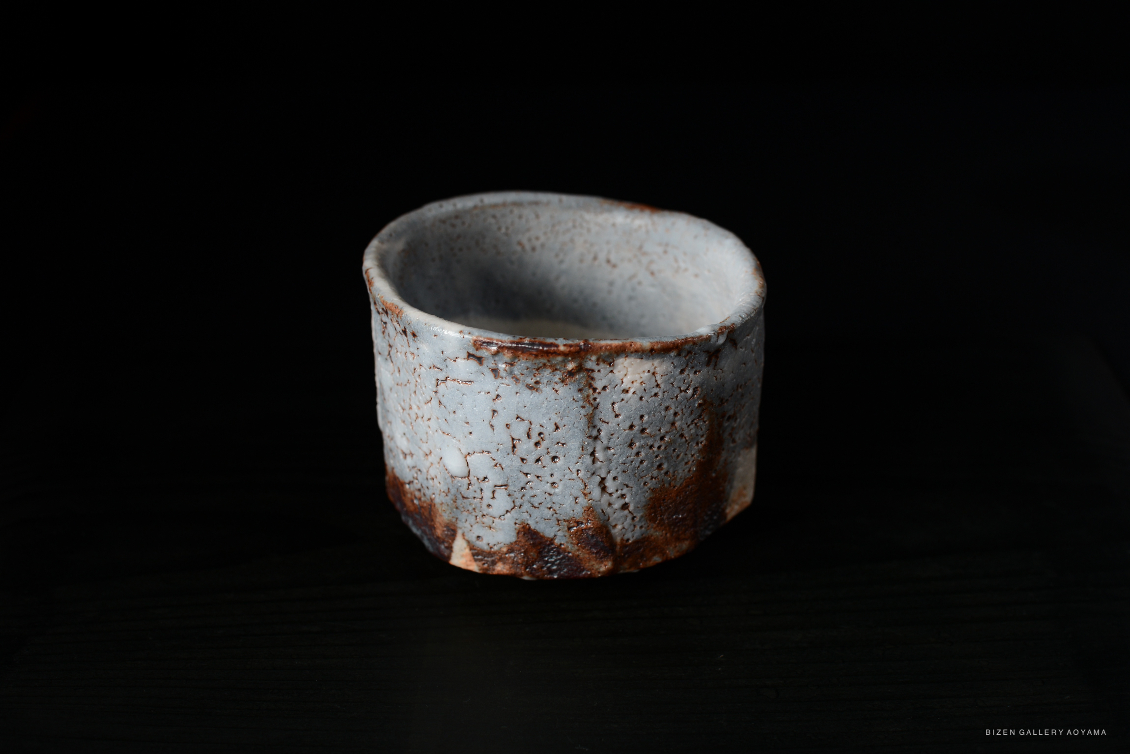A Nezumi Shino Chawan tea bowl featuring a pale blue-grey glaze with rust accents, showcasing a textured surface and unique crazing patterns.