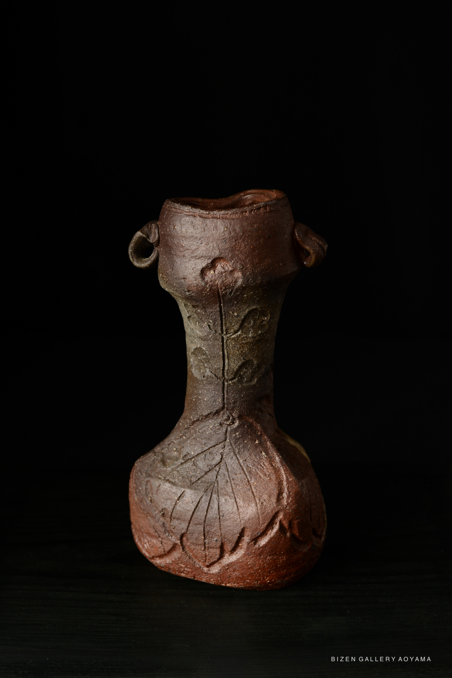 Bizen Kohjiguchi Hanaire, a ceramic vase featuring a textured surface with leaf motifs, displayed against a dark background.