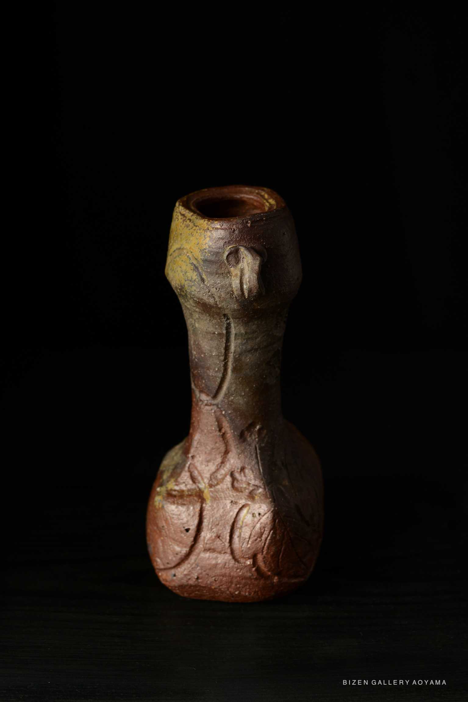 A Bizen pottery vase with a unique shape and textured surface, featuring earthy tones of brown and an ornate design.