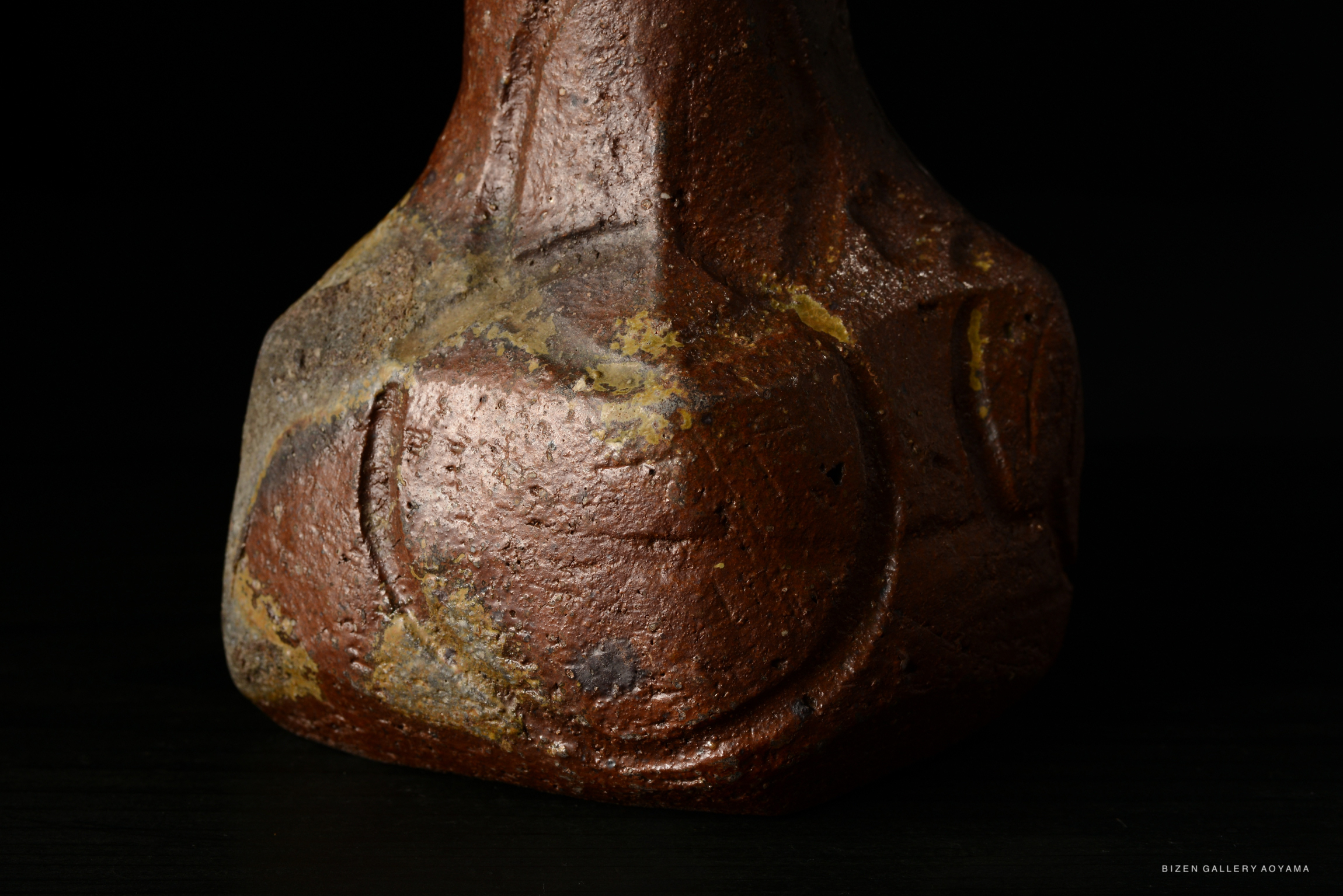 Close-up of a Bizen-style ceramic vase with a textured, earthy surface and an organic shape.