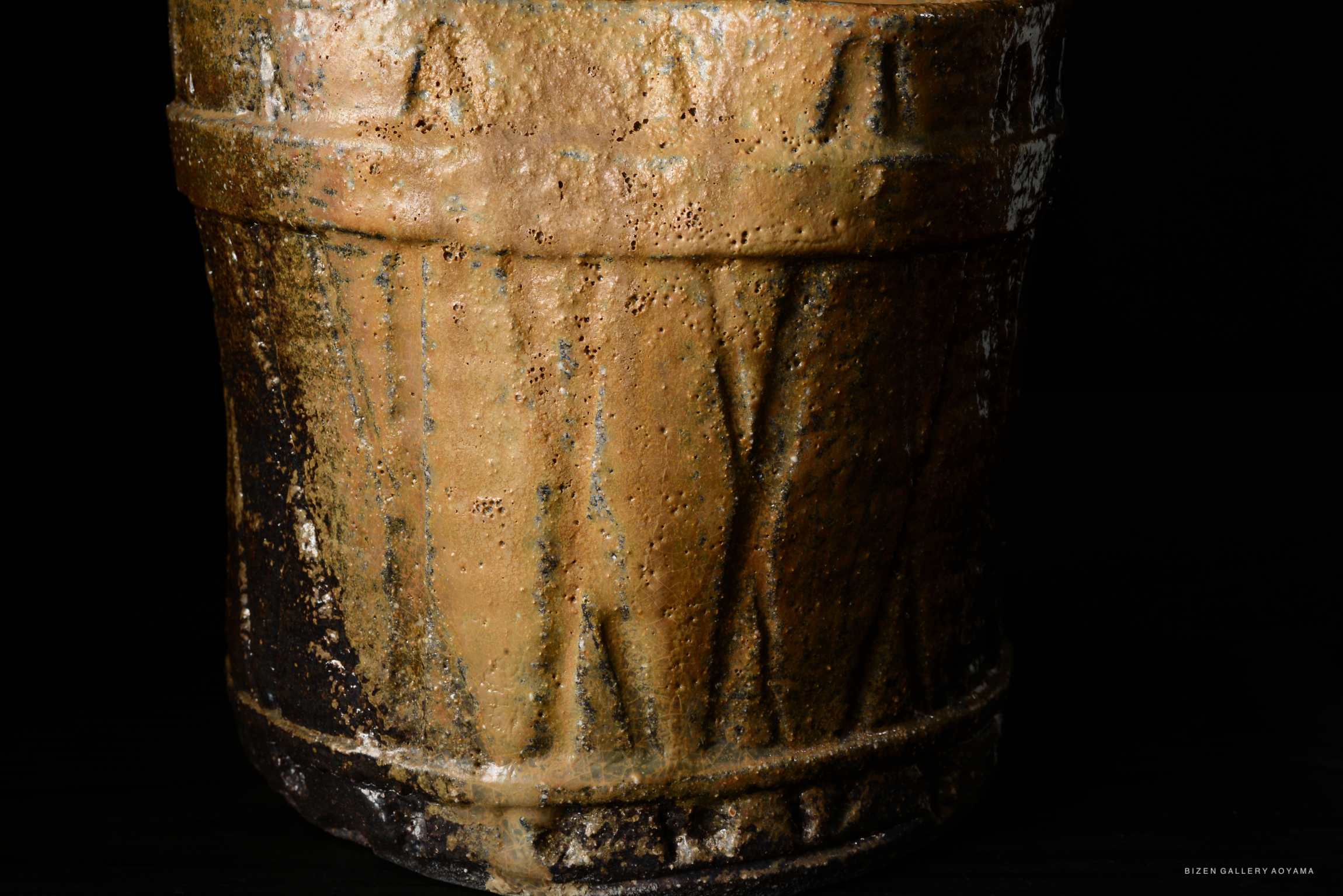 Close-up of an ornate Bizen pottery mizusashi with a rough texture and earthy colors, featuring distinguishing markings and a traditional design.