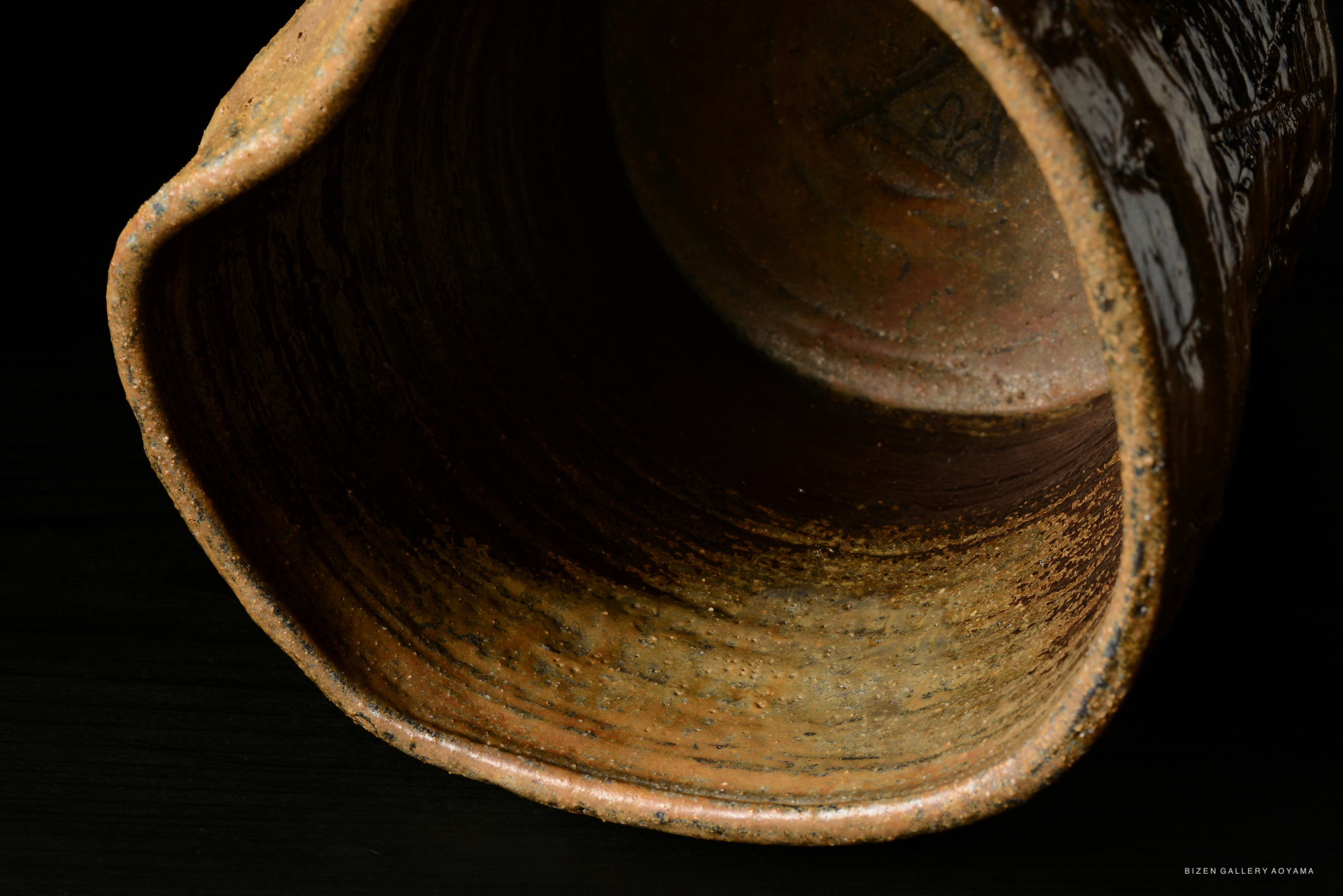 Close-up view of the interior of a textured ceramic vessel with earthy tones.