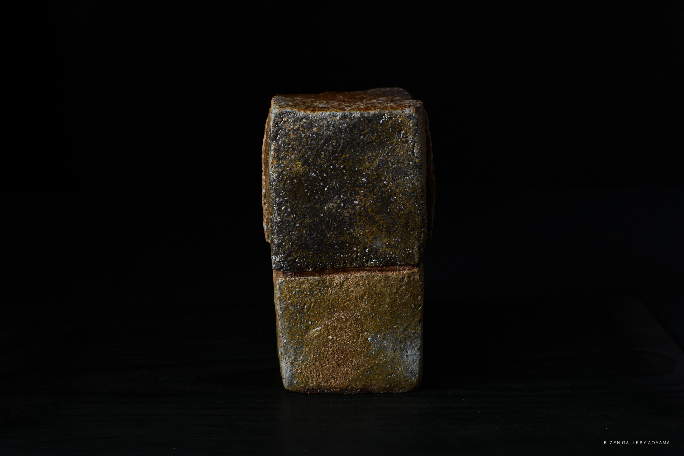 A textured ceramic piece with a dark and light brown color scheme, displayed against a black background.