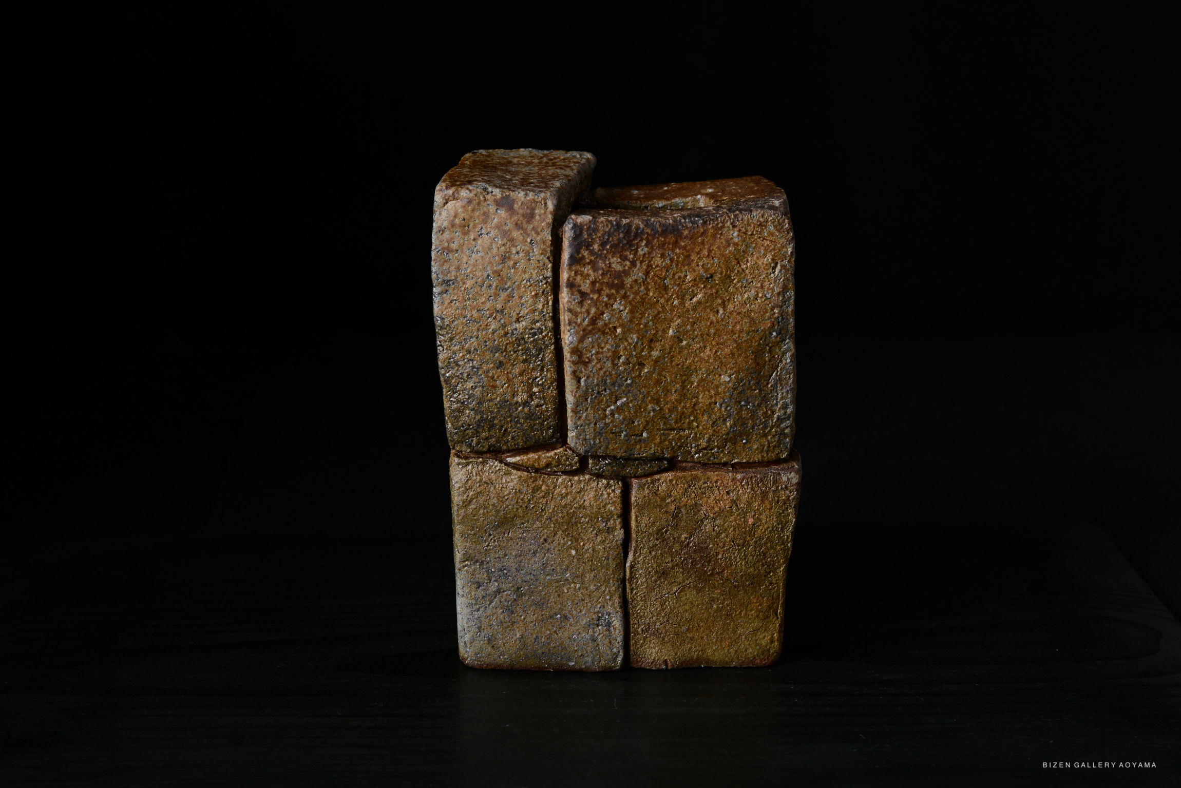 A unique, textured sculpture made of clay, displayed against a dark background.