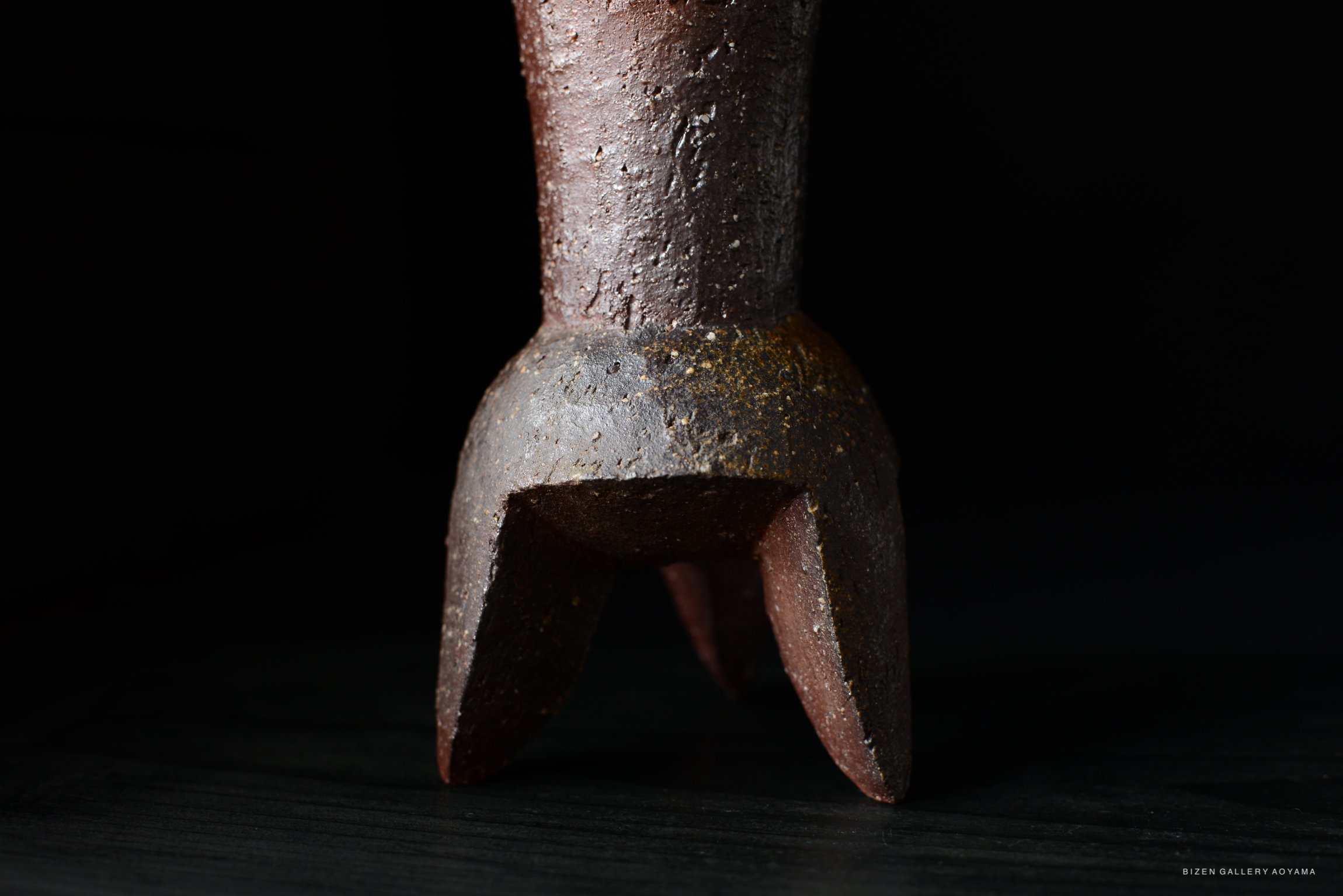 Close-up view of a clay vase base with a textured surface and a unique tripod design.