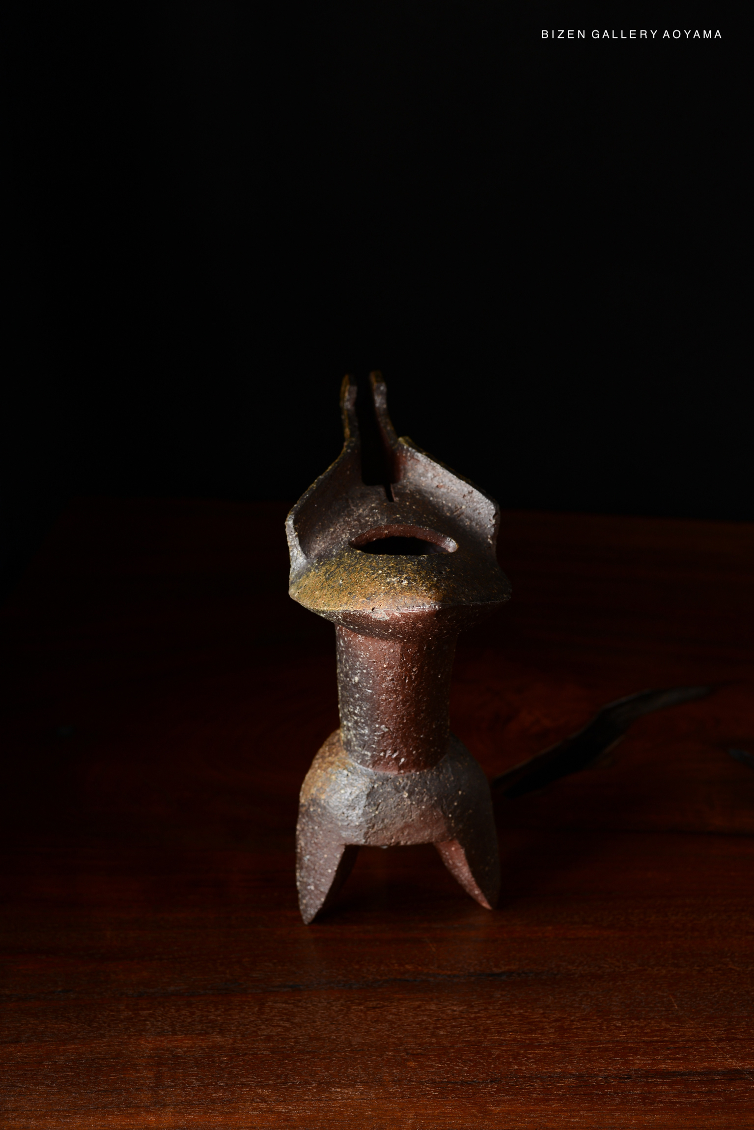 A decorative ceramic flower vase with a unique design, showcasing a rich texture and earthy colors, placed on a wooden surface against a black background.