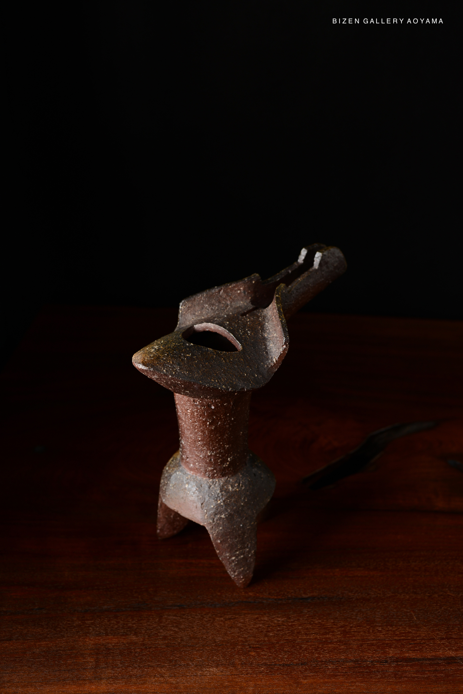 A traditional Japanese ceramic vase displayed on a dark wooden surface, showcasing its rustic texture and craftsmanship.