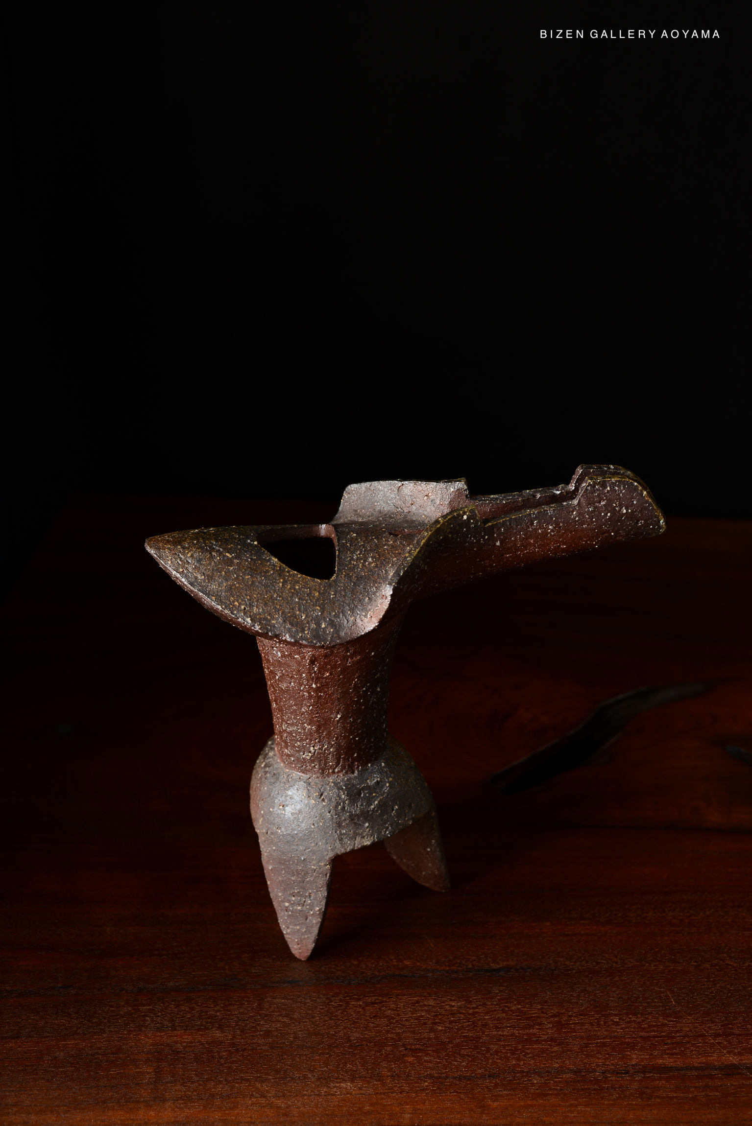 A Bizen pottery vase displayed against a black background, featuring unique textures and a sculptural design.