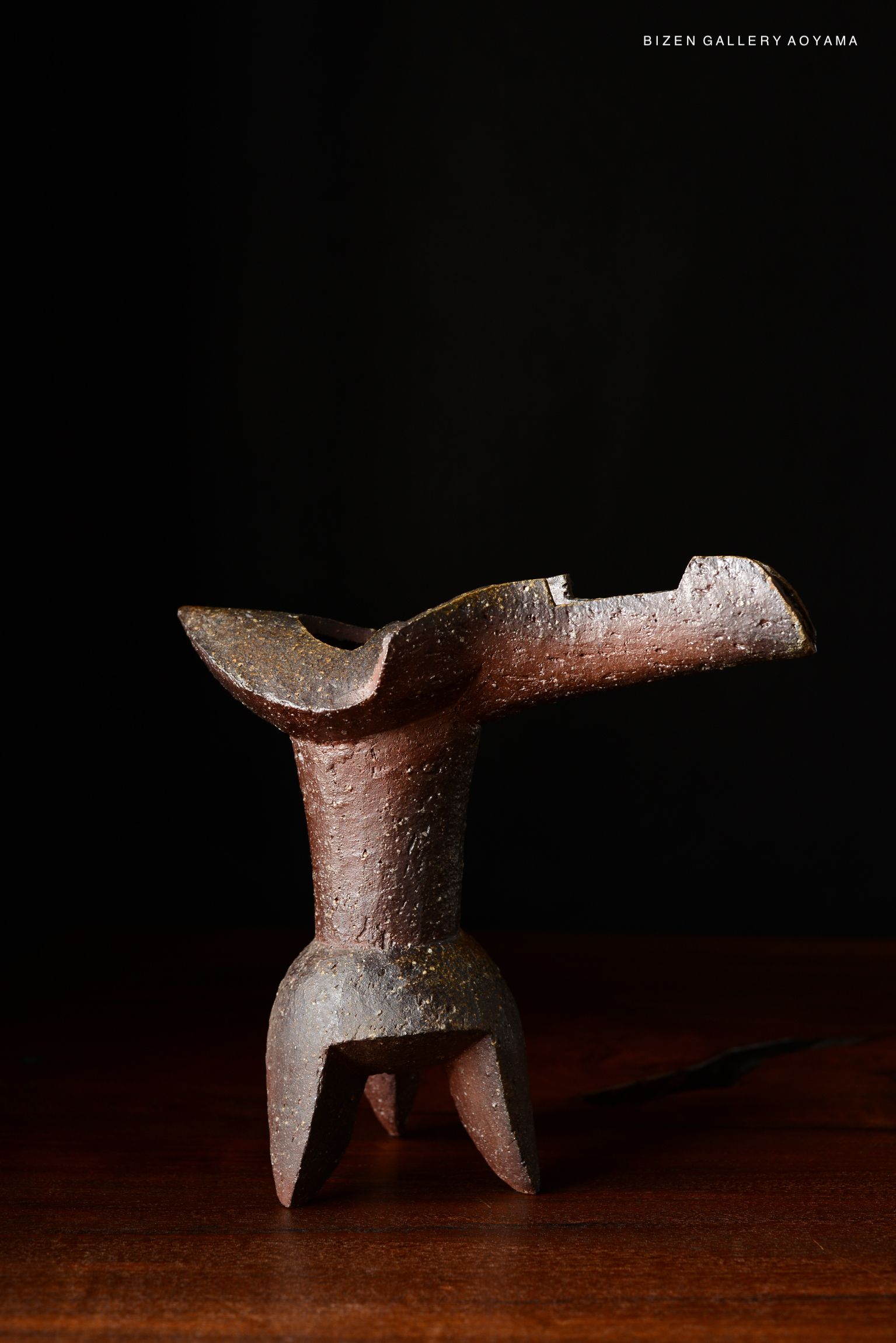 A decorative ceramic flower vase with a unique, abstract shape, set against a dark background.