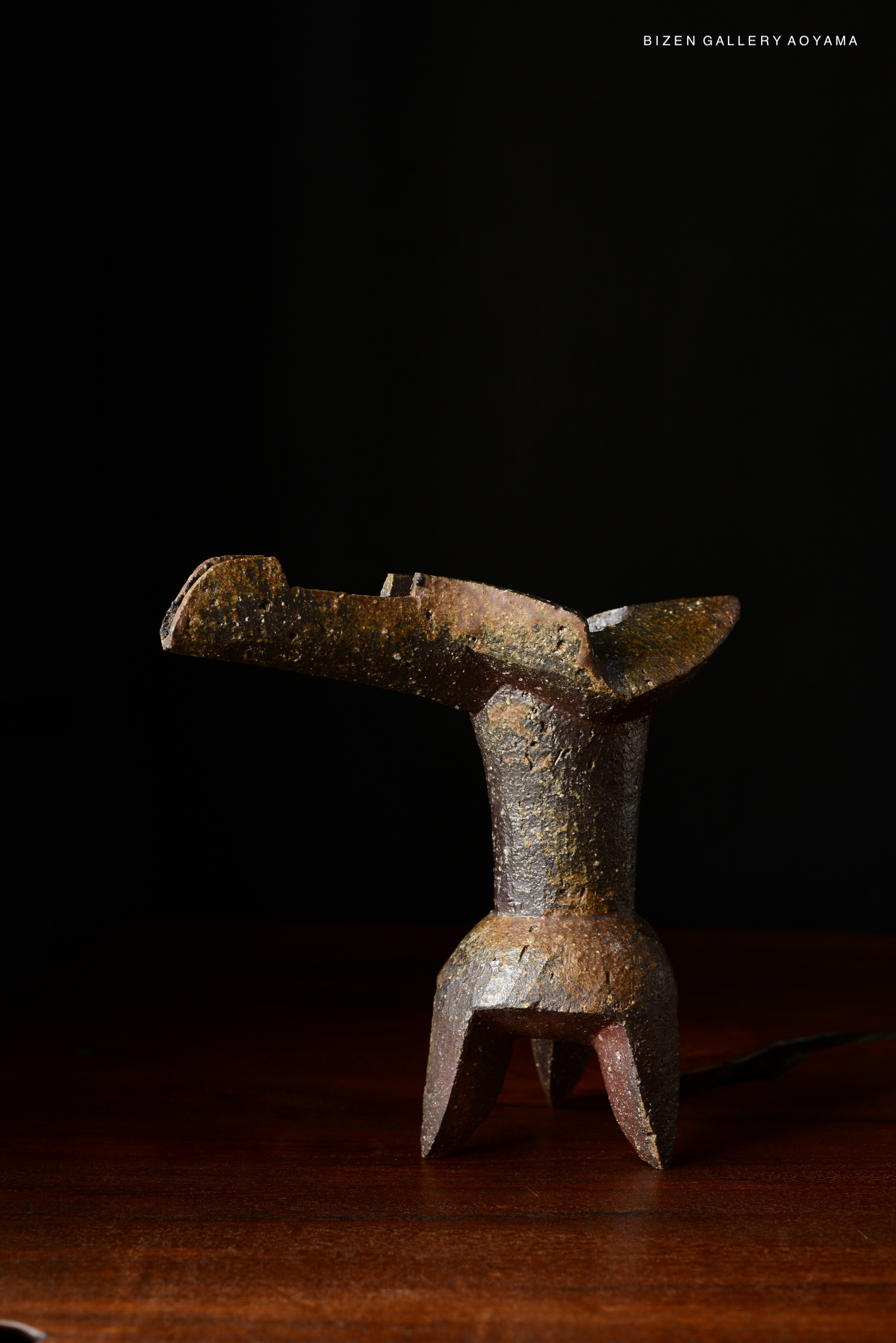 Hanaire Shaku, a unique ceramic vase with a textured surface, placed on a wooden table against a dark background.