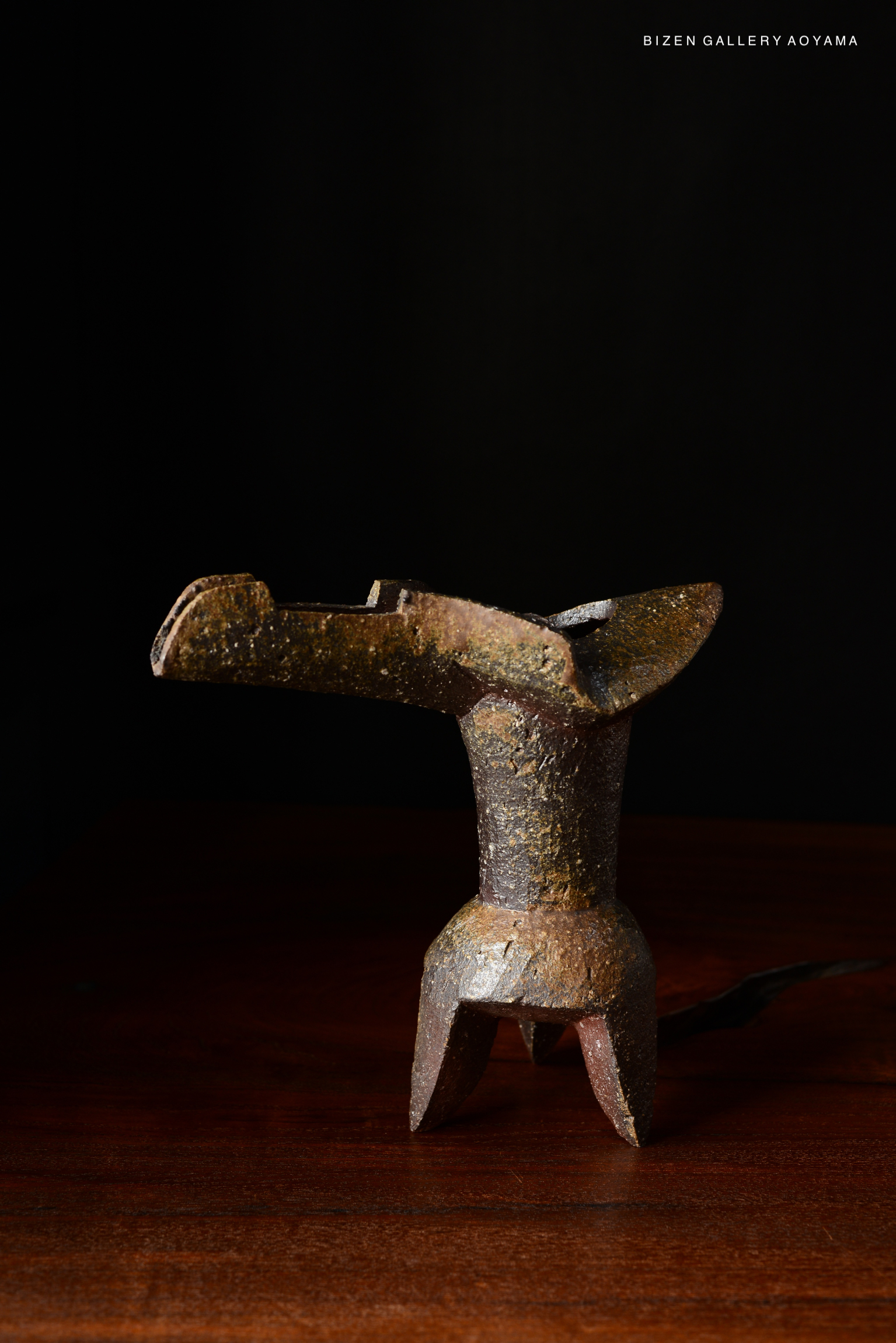 A traditional Japanese hanaire (flower vase) made of earthenware, with a rustic design, displayed on a wooden surface against a dark background.