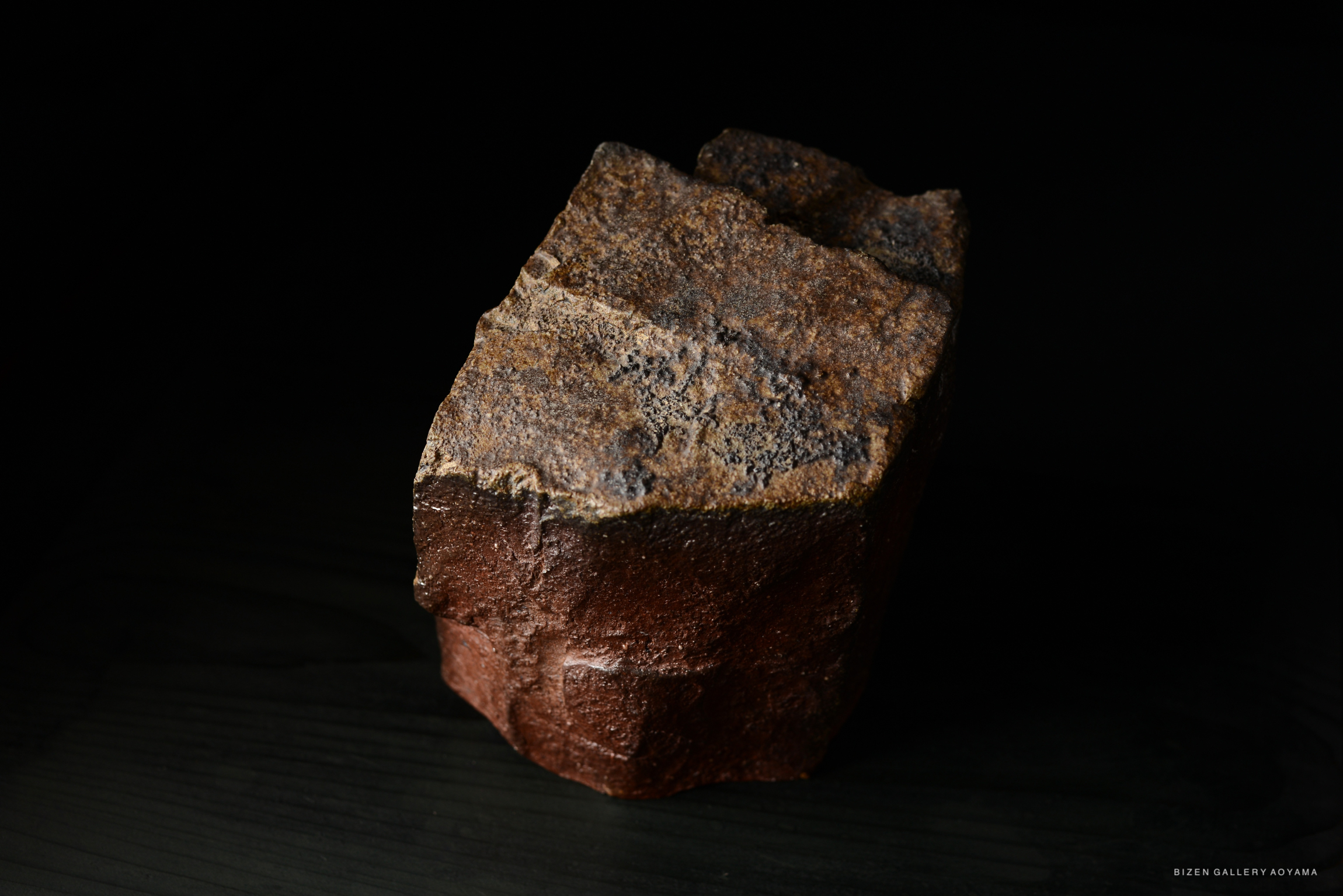 A close-up image of a textured, irregularly shaped piece of pottery against a dark background.