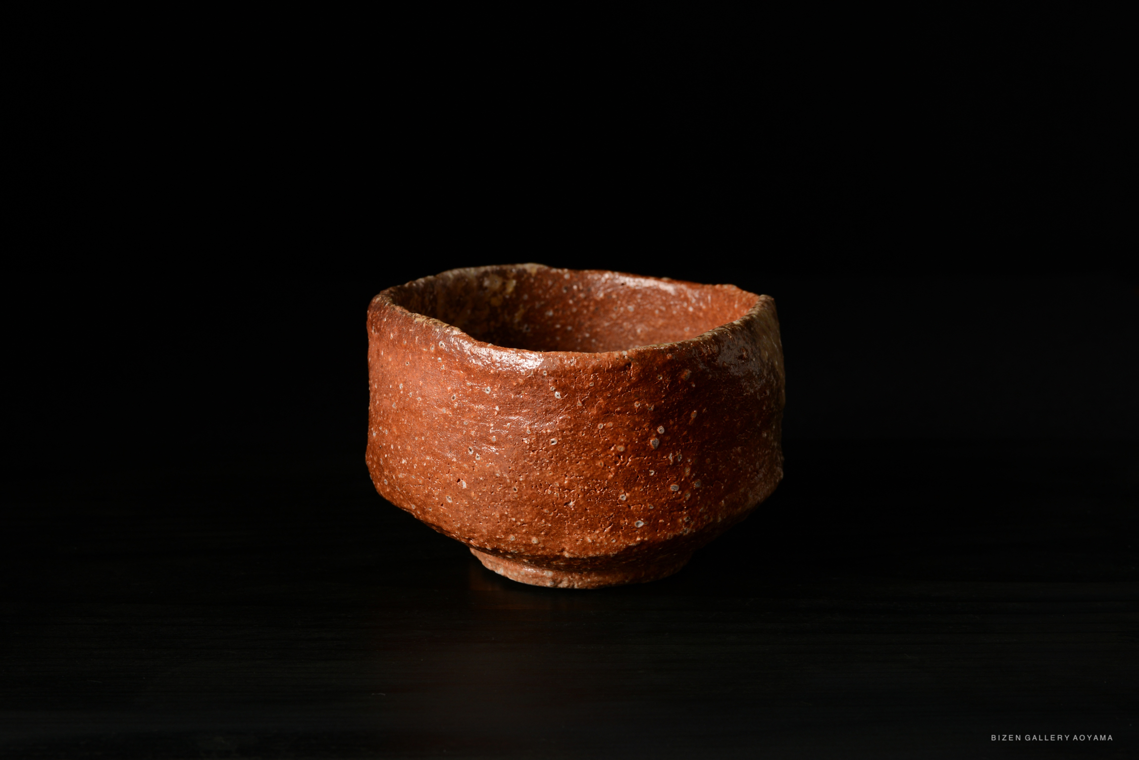 A textured, red-brown ceramic bowl against a black background.