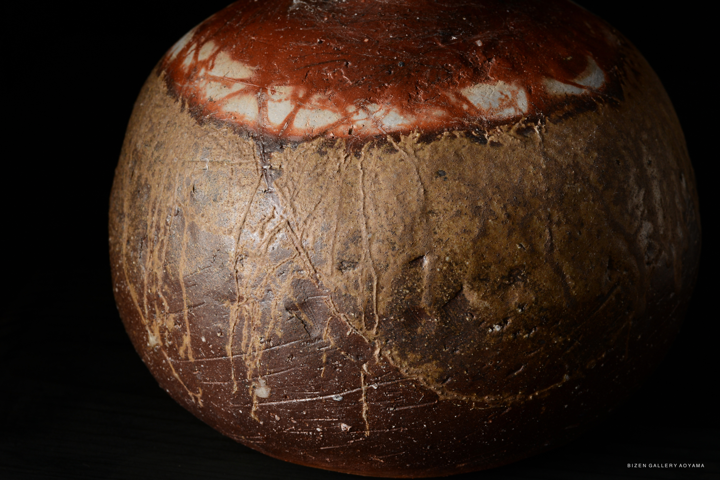 A close-up view of a Bizen pottery Tokkuri, showcasing its earthy textures and rich brown tones, with distinctive features and markings on the surface.