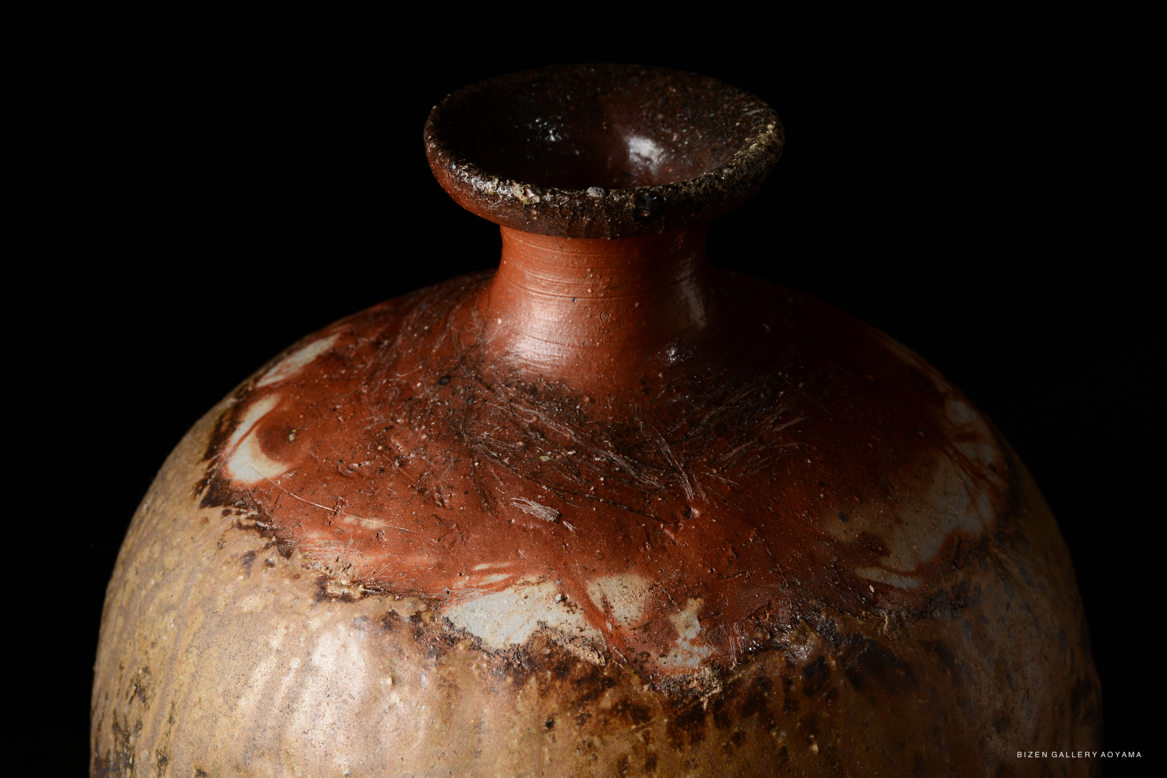 Close-up of a Bizen pottery Tokkuri with a reddish-brown glaze and a narrow neck.