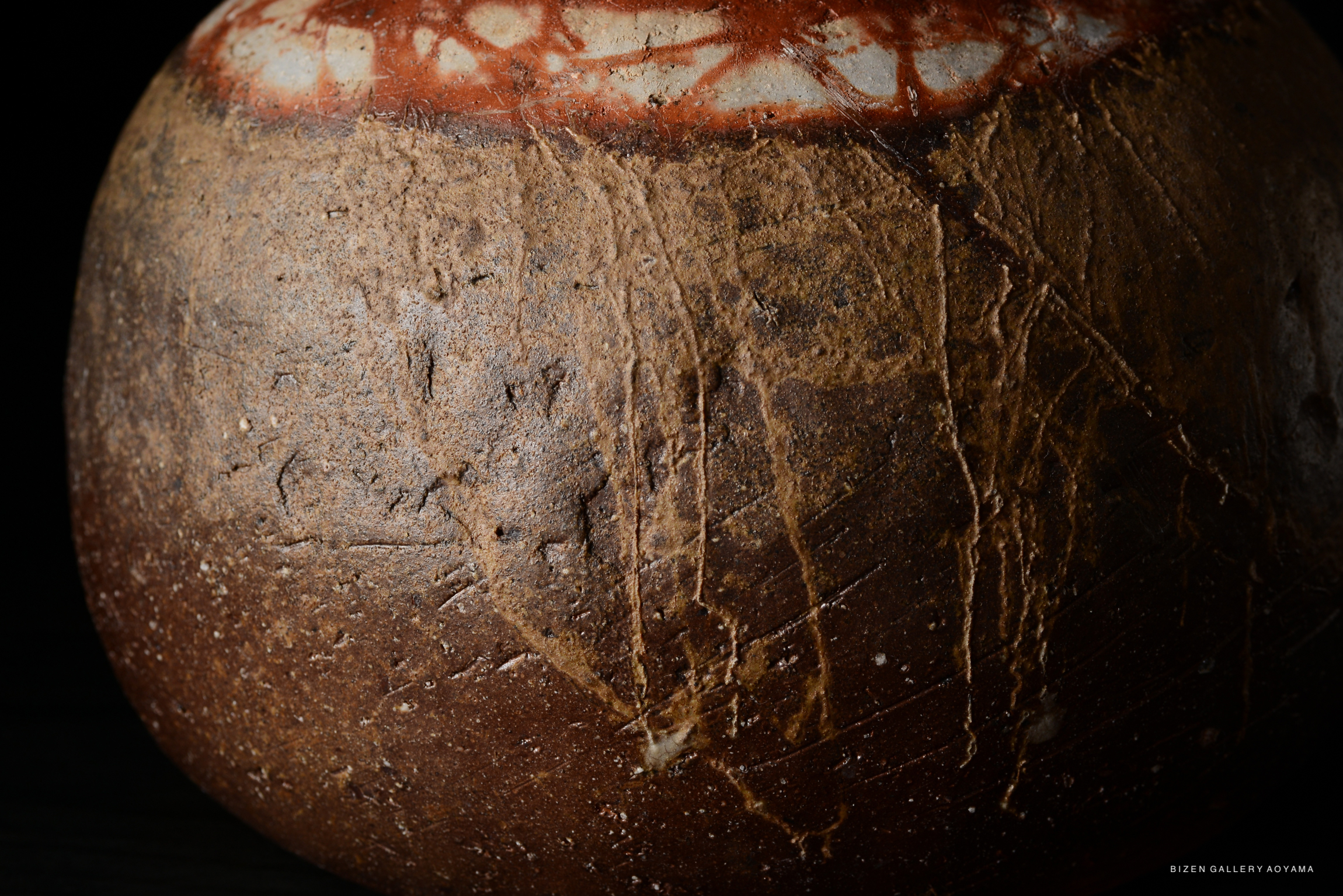Close-up view of the textured surface of a Bizen O Kabura Tokkuri, featuring earthy tones and intricate patterns.