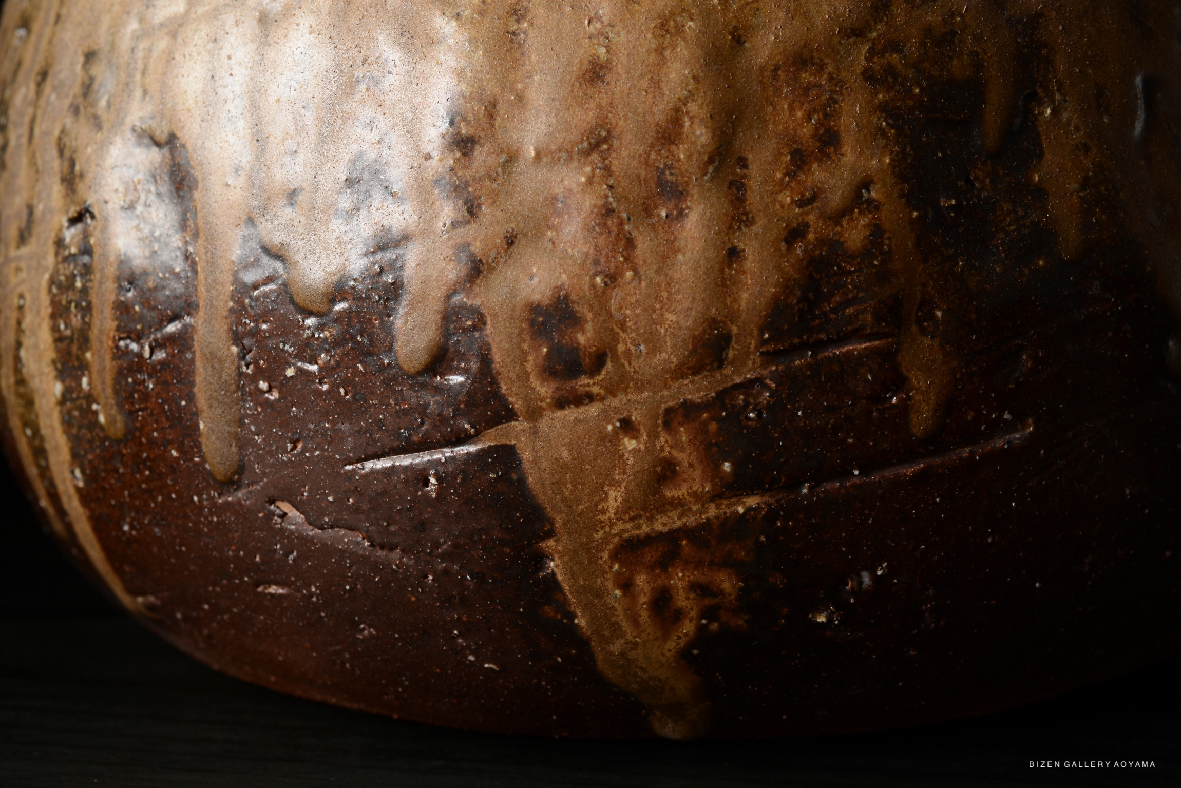 Close-up of the textured surface of a Bizen ceramic Tokkuri, showcasing earthy brown tones and unique glaze drippings.