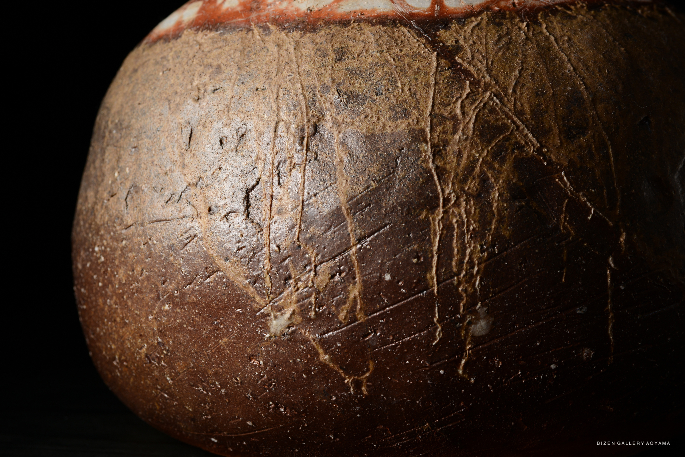 Close-up of the surface of a Bizen pottery tokkuri, showcasing its textured earthy colors and unique patterns.