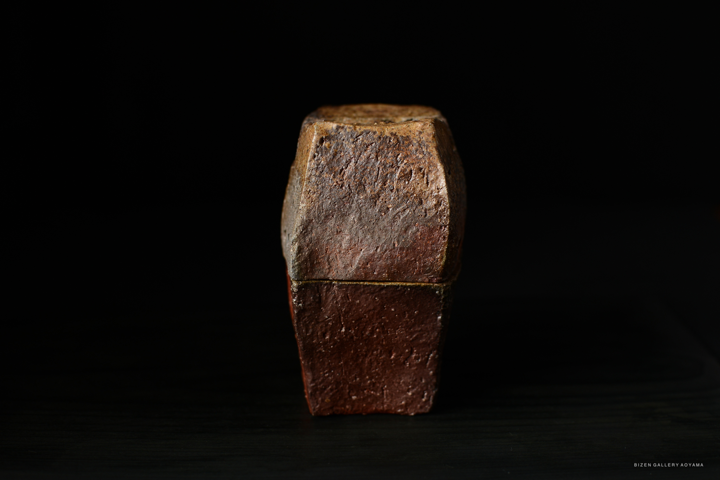 A rustic incense burner made of clay with a textured reddish-brown finish, displayed against a dark background.