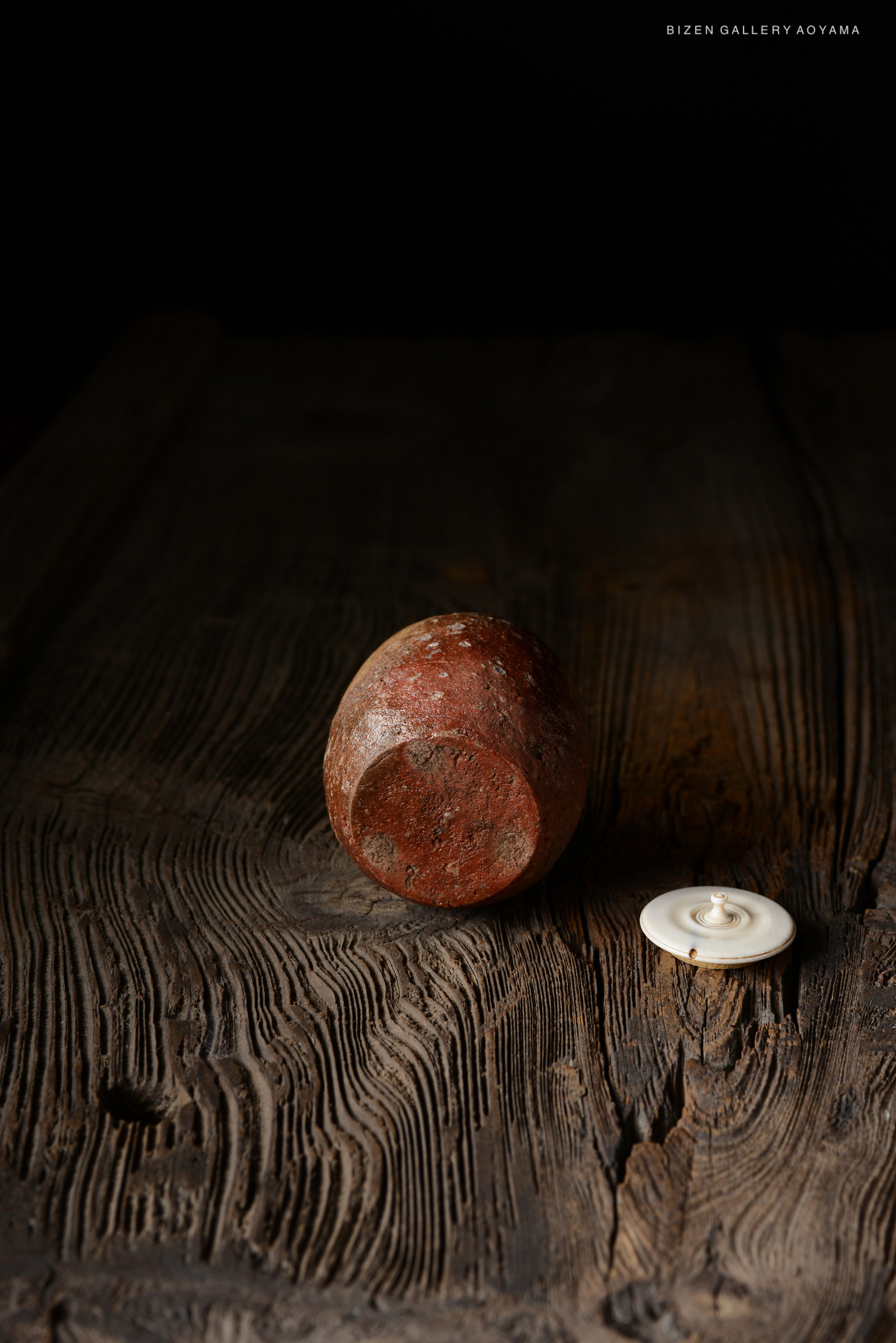 A Shigaraki Chaire, an engraved pottery tea container, displayed on a wooden surface with a dark background.