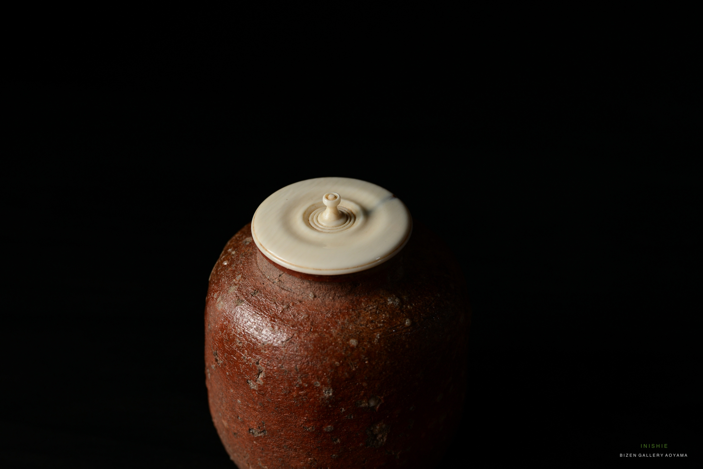 A close-up view of a Shigaraki Chaire, a traditional Japanese tea container, featuring a textured brown body and a smooth light-colored lid.