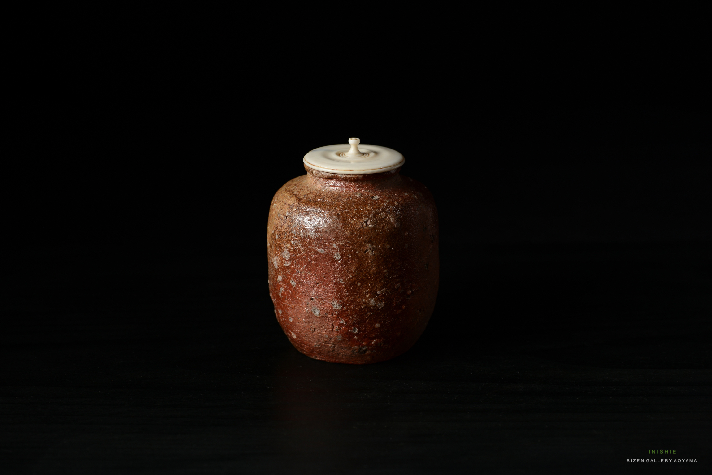 A Shigaraki Chaire, a traditional Japanese tea container, with an engraved signature 'Reisetsu' on a dark background.