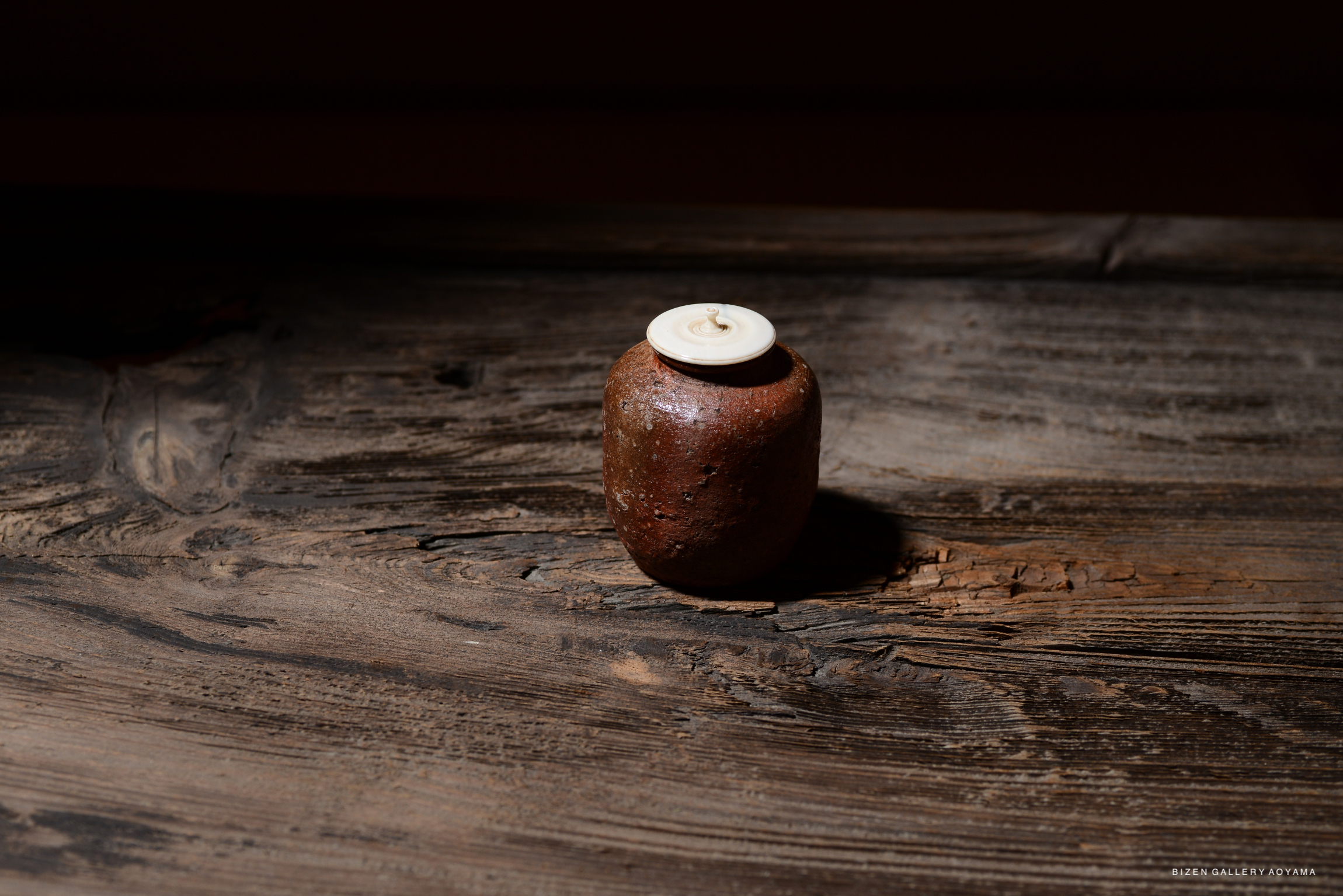 A Shigaraki chaire (tea container) with an engraved signature 'Reisetsu' displayed on a wooden surface.