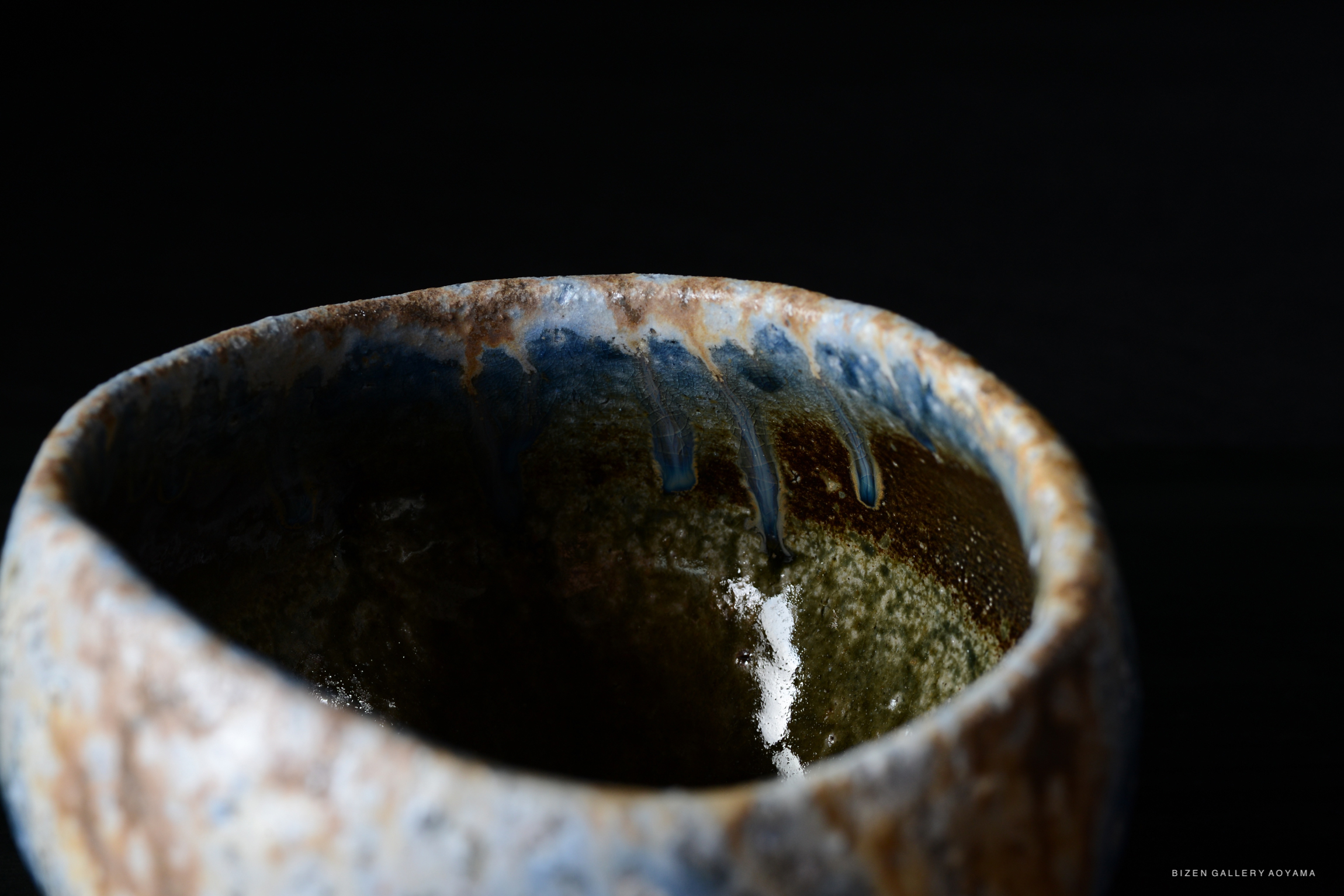 Close-up view of a handcrafted pottery bowl showing intricate glazing with a mix of blue and brown colors.