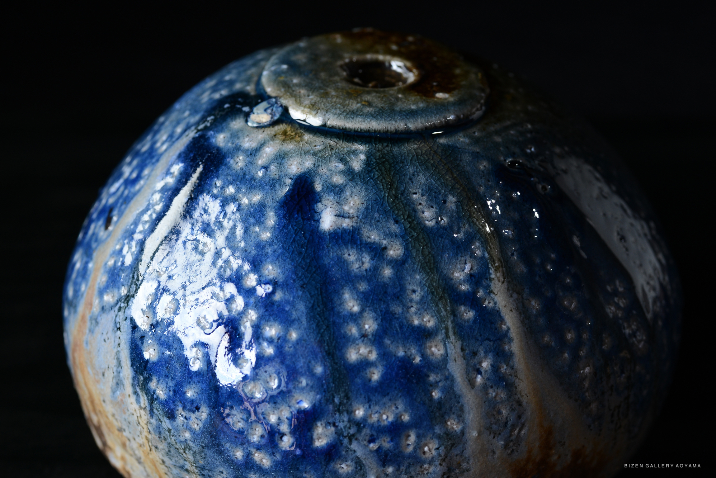 Close-up of a blue glazed ceramic bowl showcasing intricate patterns and textures.