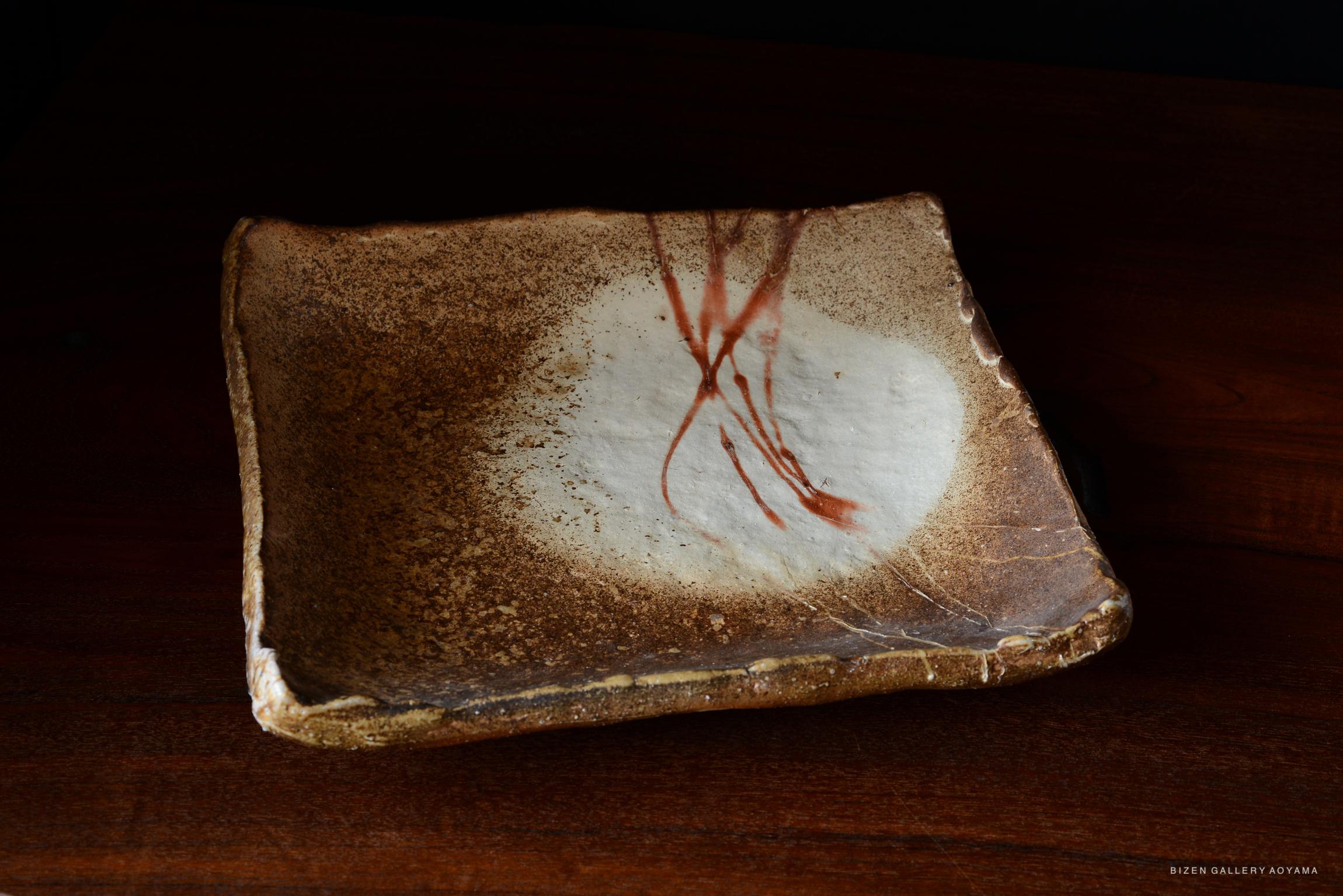 A square Bizen pottery plate with a subtle brown and white glaze, featuring delicate red streaks in an artistic design.
